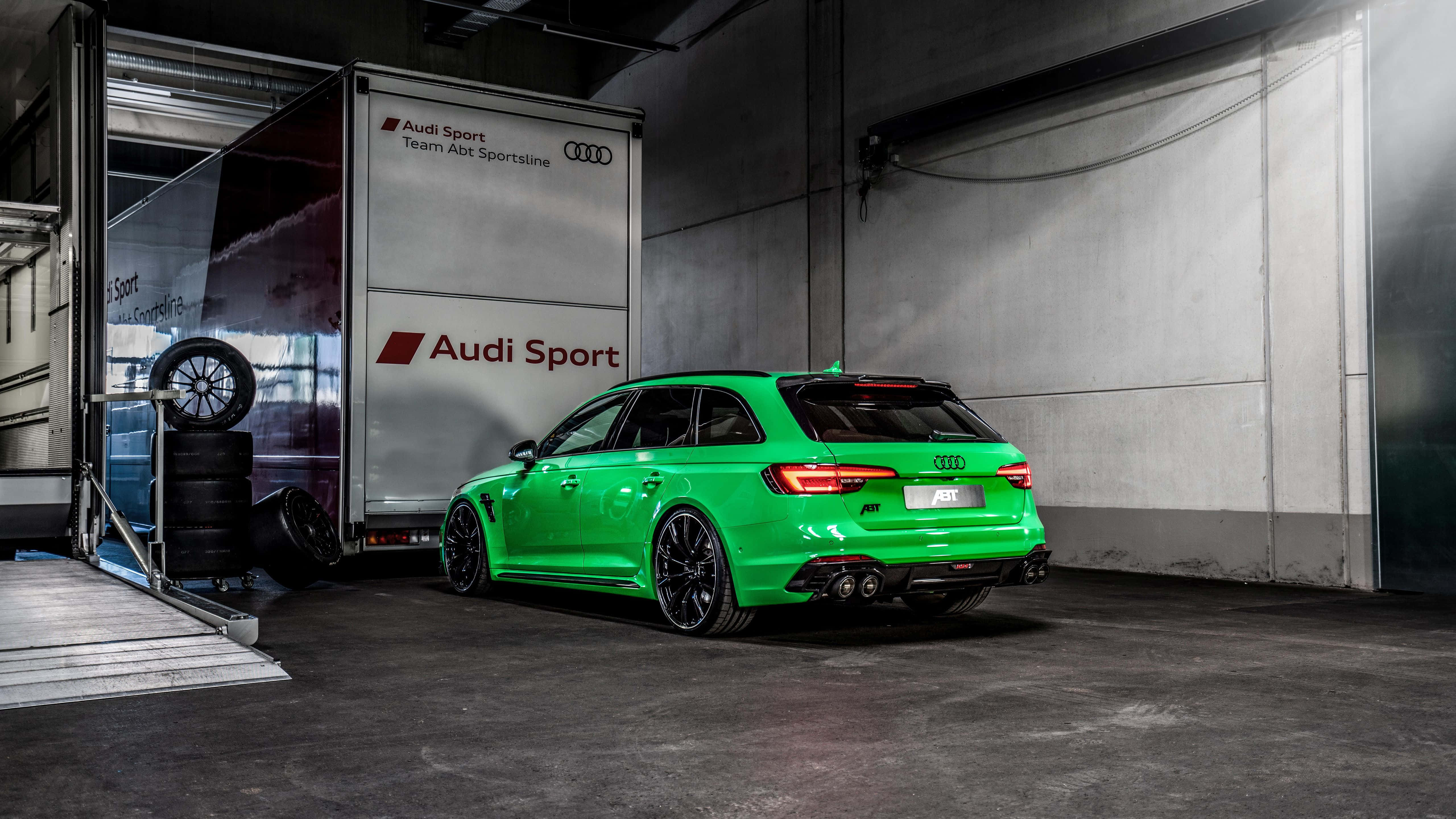 Audi Rs5 桌布 壁紙 — 一輛充滿活力的綠色Audi RS4 Avant性能旅行車停放在混凝土車庫中，旁邊是一輛Audi Sport拖車。