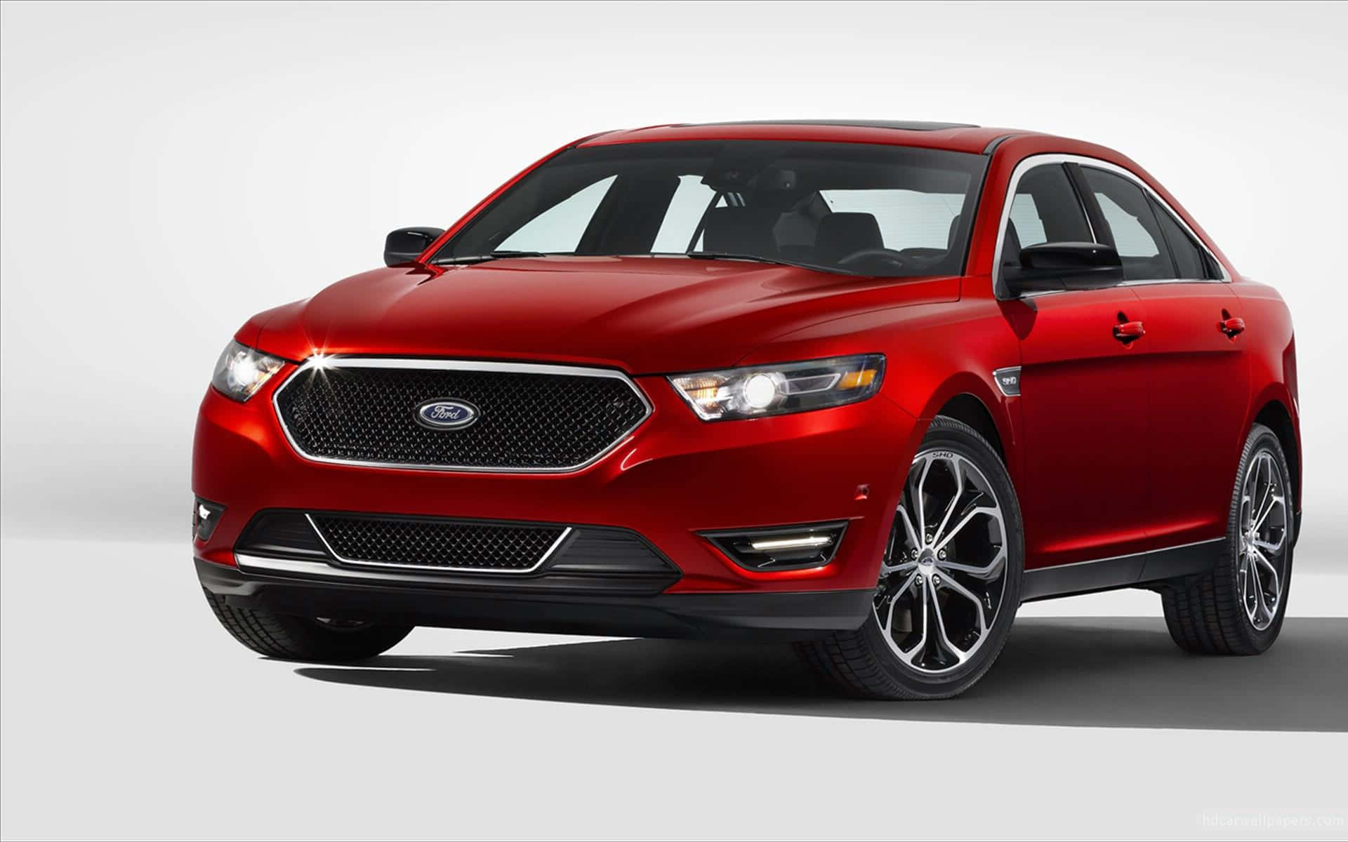 Ford Taurus 桌布 壁紙 — 一輛光澤的紅色福特 Taurus 轎車在白色背景的攝影棚燈光下閃耀。