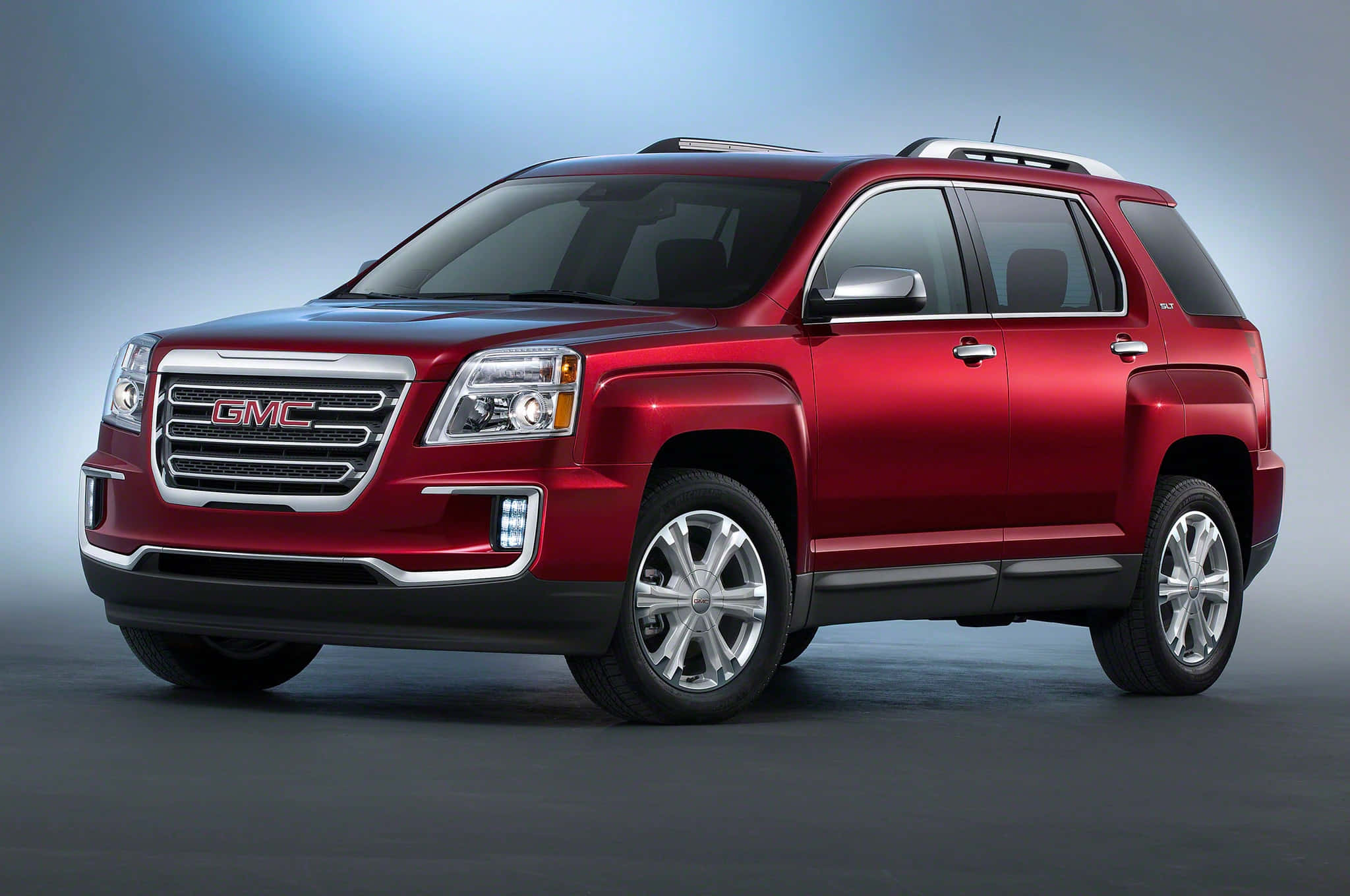 Gmc Terrain 桌布 壁紙 — 一輛光澤的紅色GMC Acadia SUV在柔和藍色燈光和灰色漸變背景的攝影棚中展示。