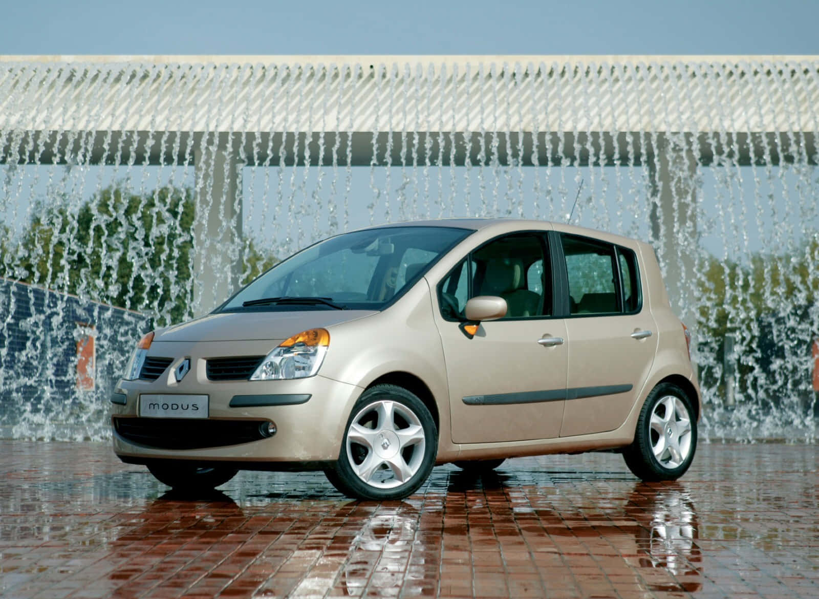 Renault Modus 桌布 壁紙 — 一輛米色雷諾Modus停泊在濕紅磚路面，背後有流水牆，上方是晴朗藍天。