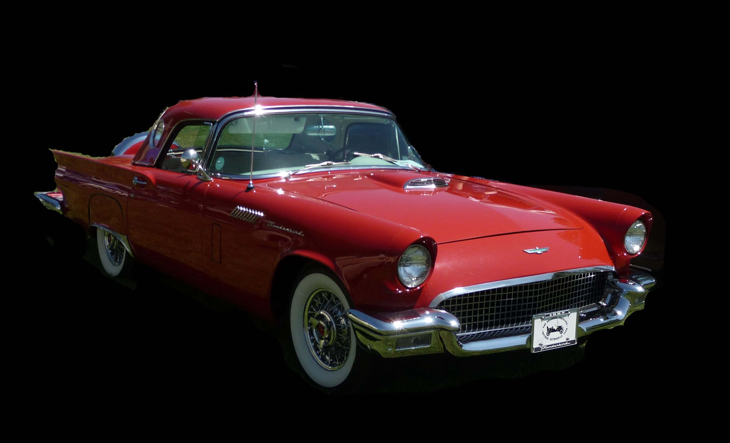 Ford Thunderbird 桌布 壁紙 — 一輛閃亮的紅色1950年代福特雷鳥經典車，帶有鍍鉻裝飾和白色輪胎，在純黑色背景下脫穎而出。