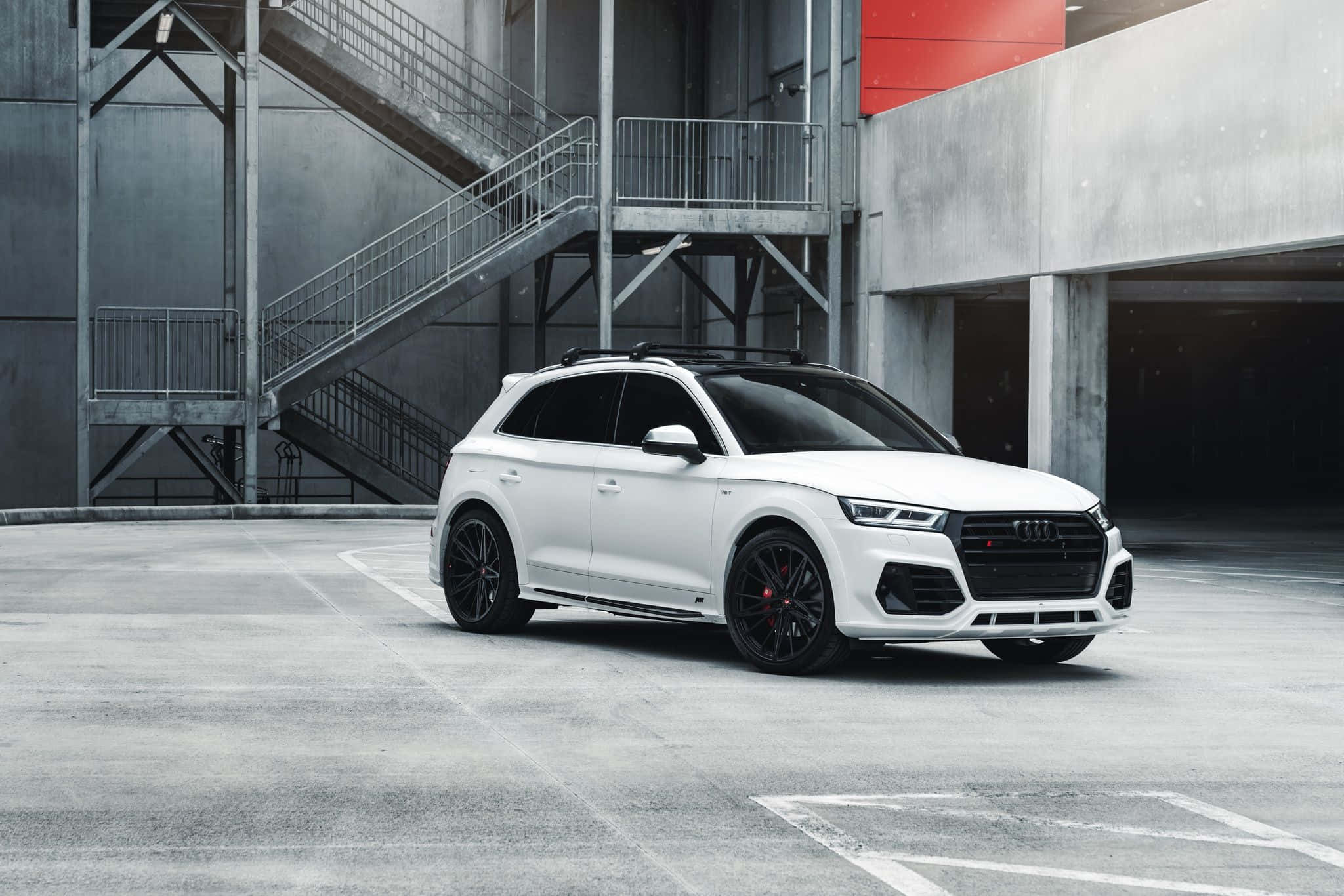 Audi Q5 桌布 壁紙 — 一輛時尚的白色奧迪SQ5 SUV配黑色輪圈，停放在工業照明下的現代混凝土停車場。