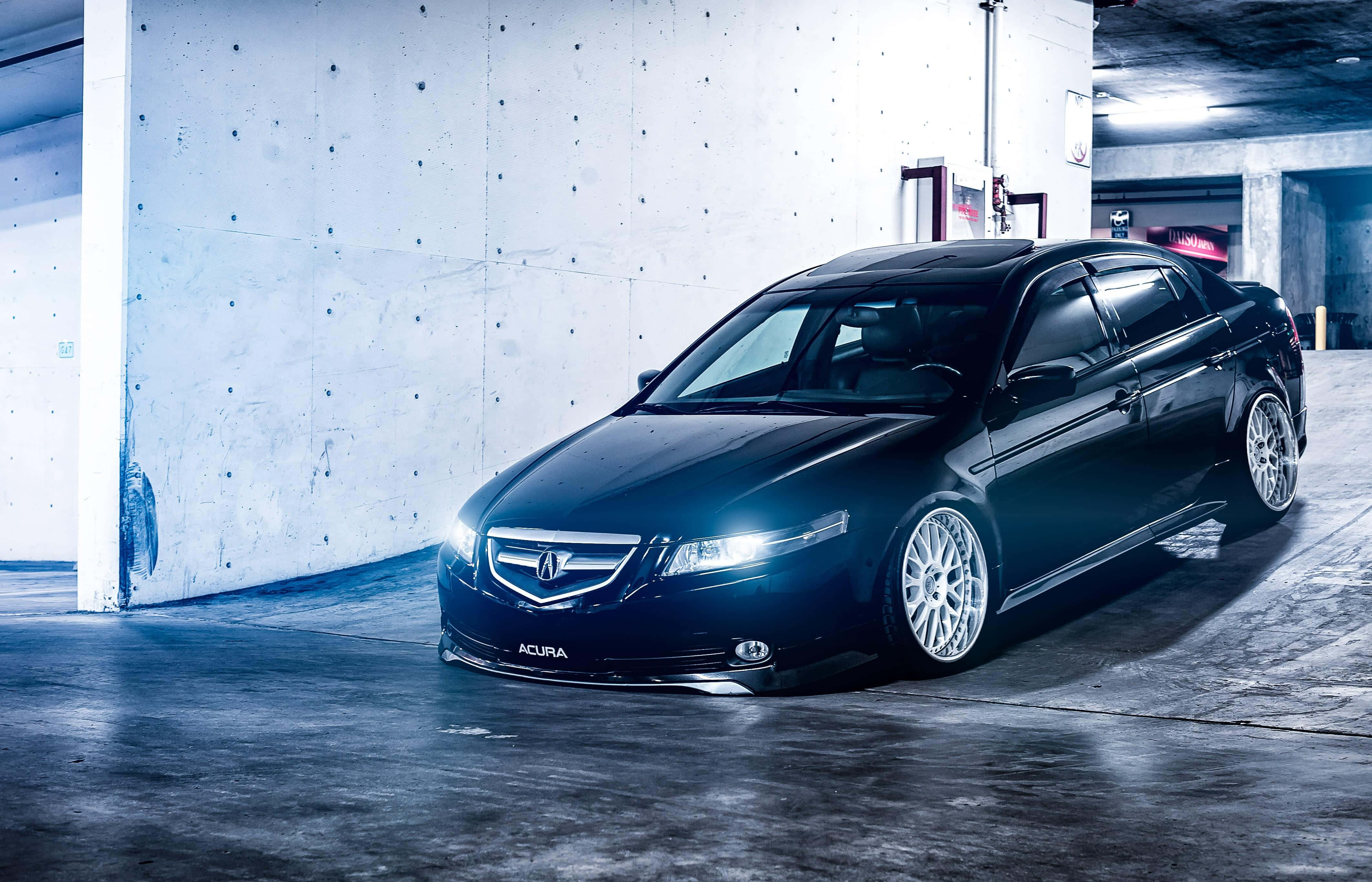 Acura Tsx 桌布 壁紙 — 一輛時尚的黑色Acura轎車，車頭燈發光，停在昏暗的混凝土車庫中，燈光為冷藍色。