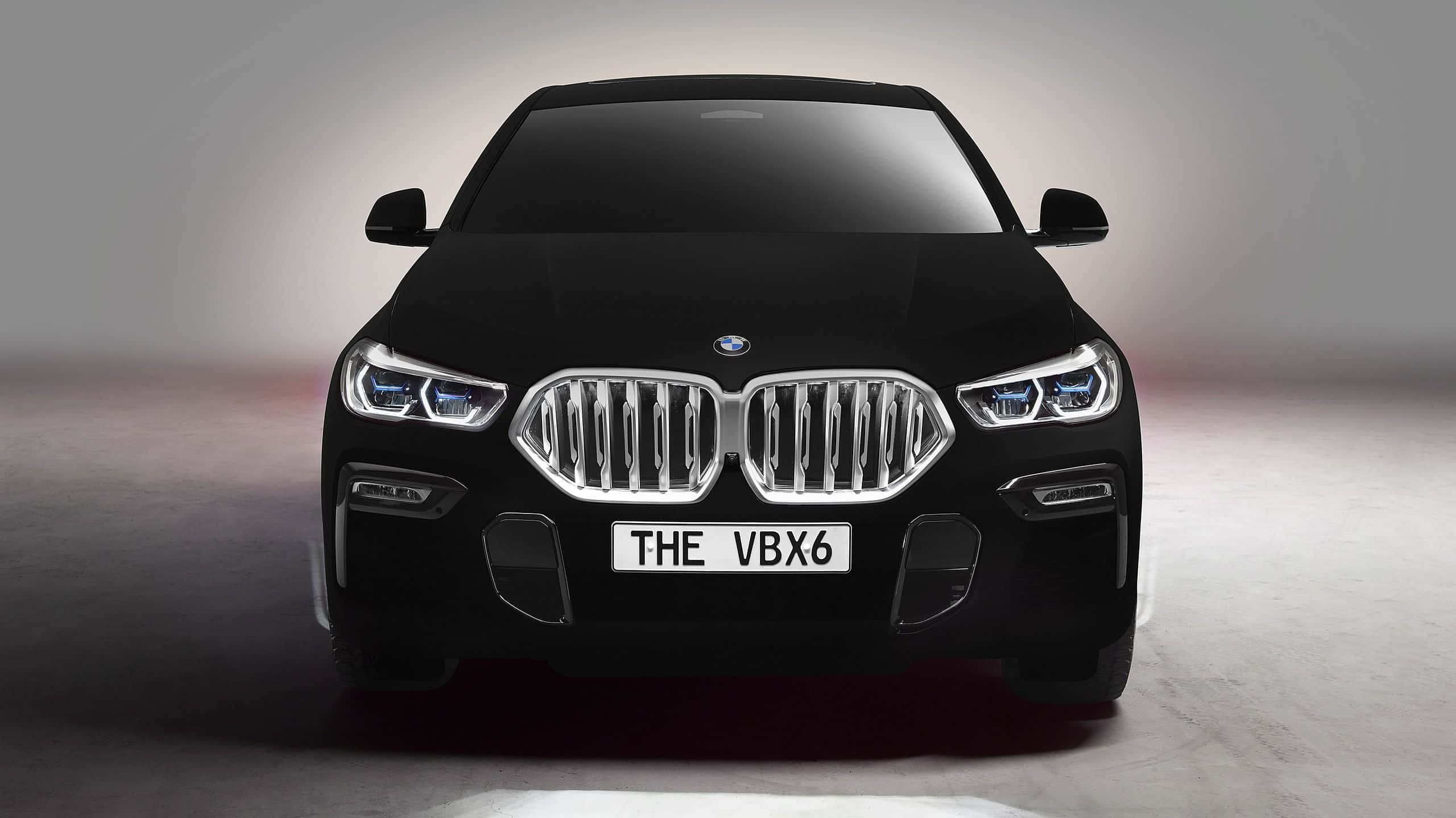 Bmw X6 桌布 壁紙 — 一輛時尚的黑色BMW X6在極簡風格的攝影棚中正面朝前，配備發光的頭燈和鍍鉻格柵。