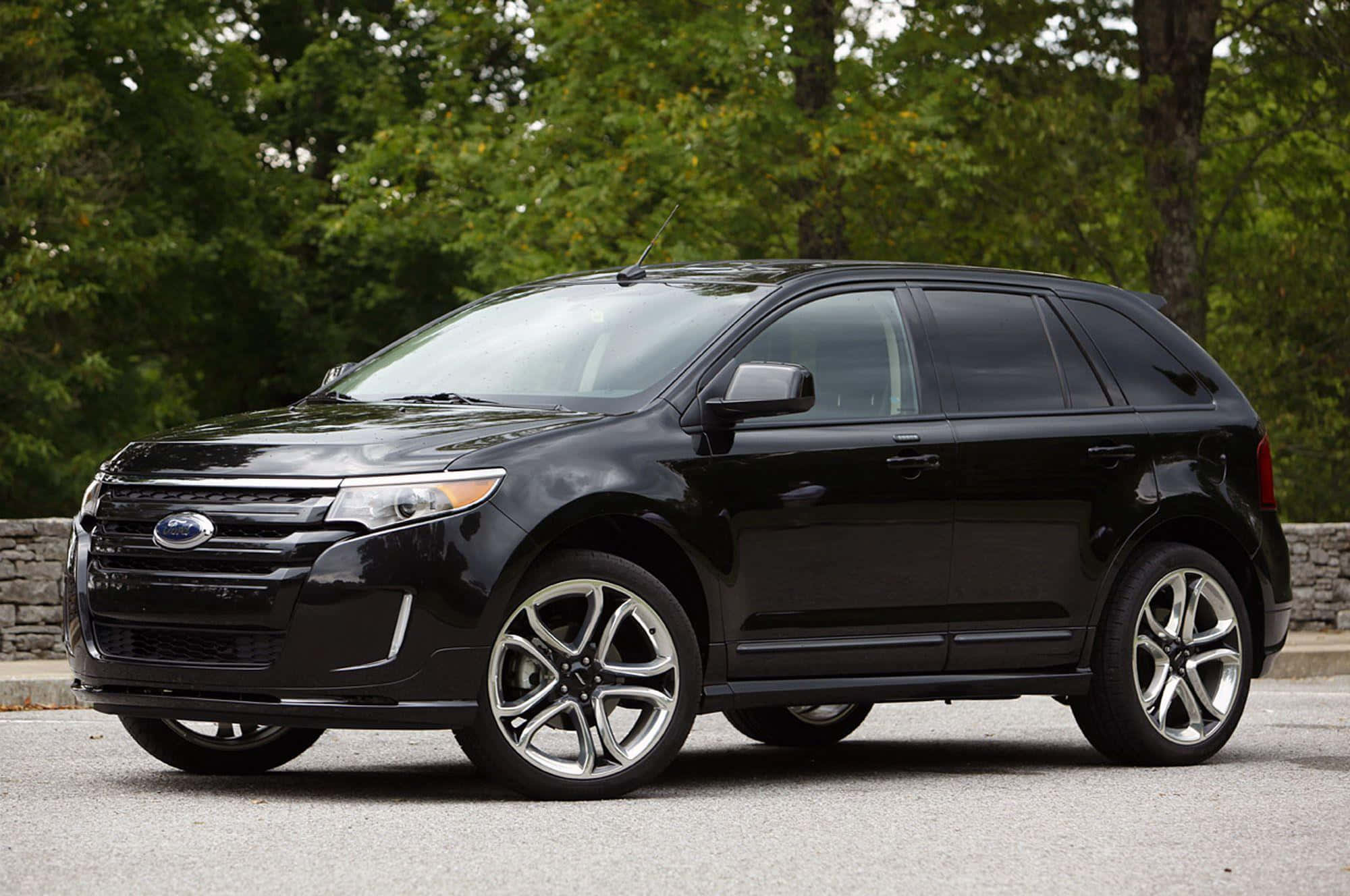 Ford Edge 桌布 壁紙 — 一輛時尚的黑色福特 Edge SUV 停在瀝青路上，背景是茂密的綠色樹木。