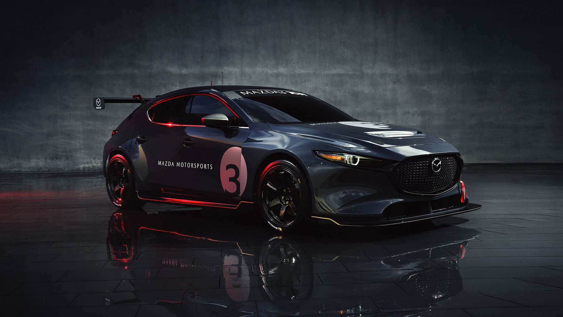 Mazda 3 Hatchback 桌布 壁紙 — 一輛時尚的黑色萬事得賽車，帶有紅色點綴和數字3，在氣氛濃厚的攝影棚燈光下，戲劇性地站在反光的深色地板上。