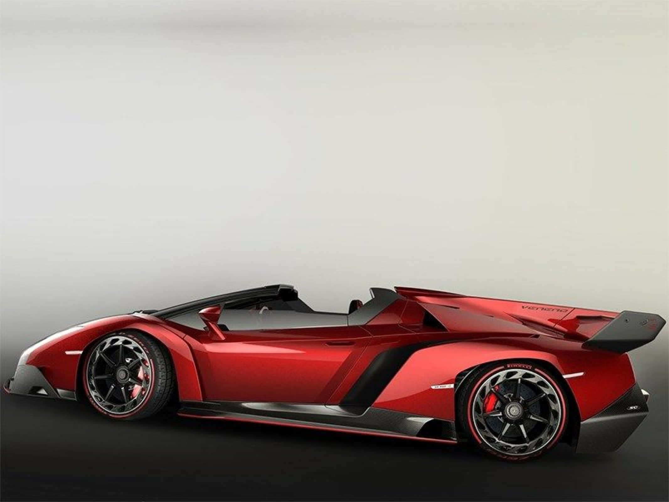 Lamborghini Veneno 桌布 壁紙 — 一輛時尚的紅色林寶堅尼 Veneno Roadster，帶有黑色飾件和空氣動力學設計，在工作室燈光下展示。