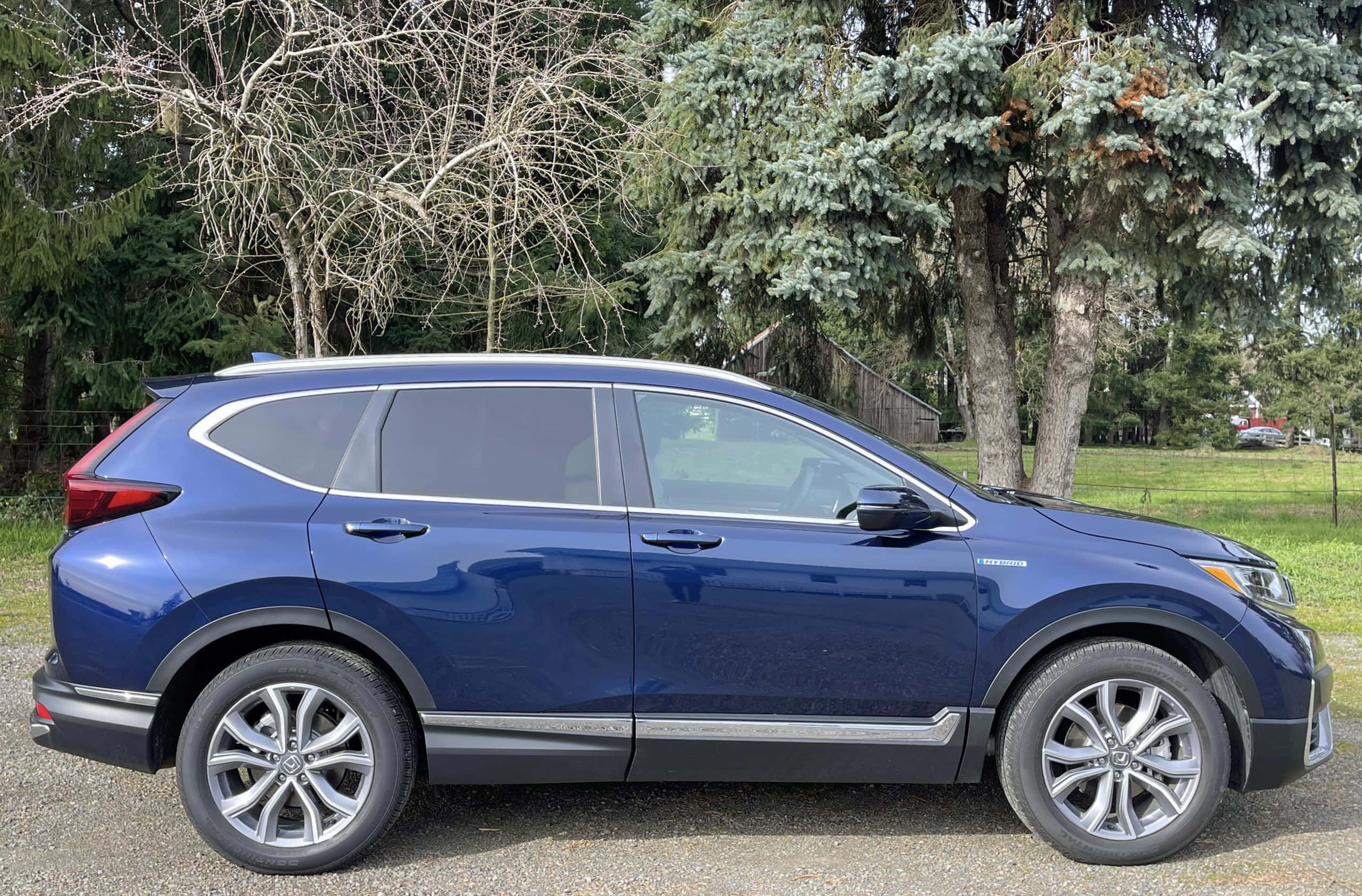 Honda Cr-v 桌布 壁紙 — 一輛時尚的藍色本田CR-V SUV停在碎石上，背景有樹木和草地。