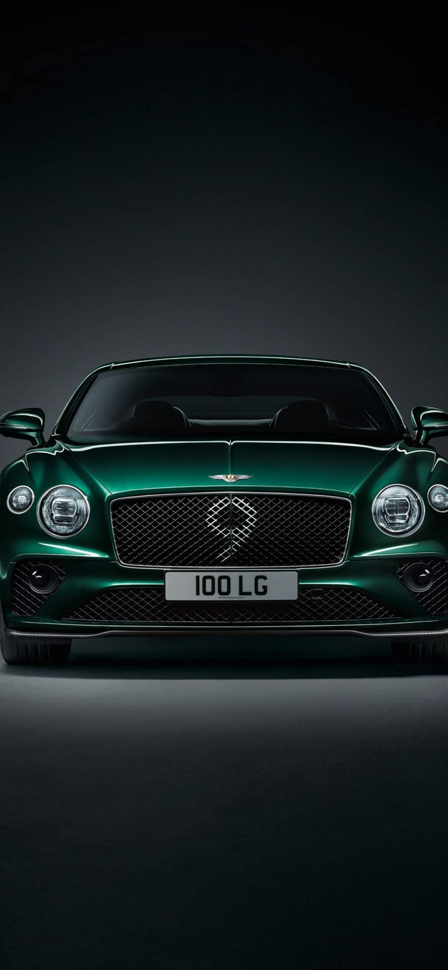 在攝影棚燈光下，深色背景中的綠色 Bentley 豪華車。