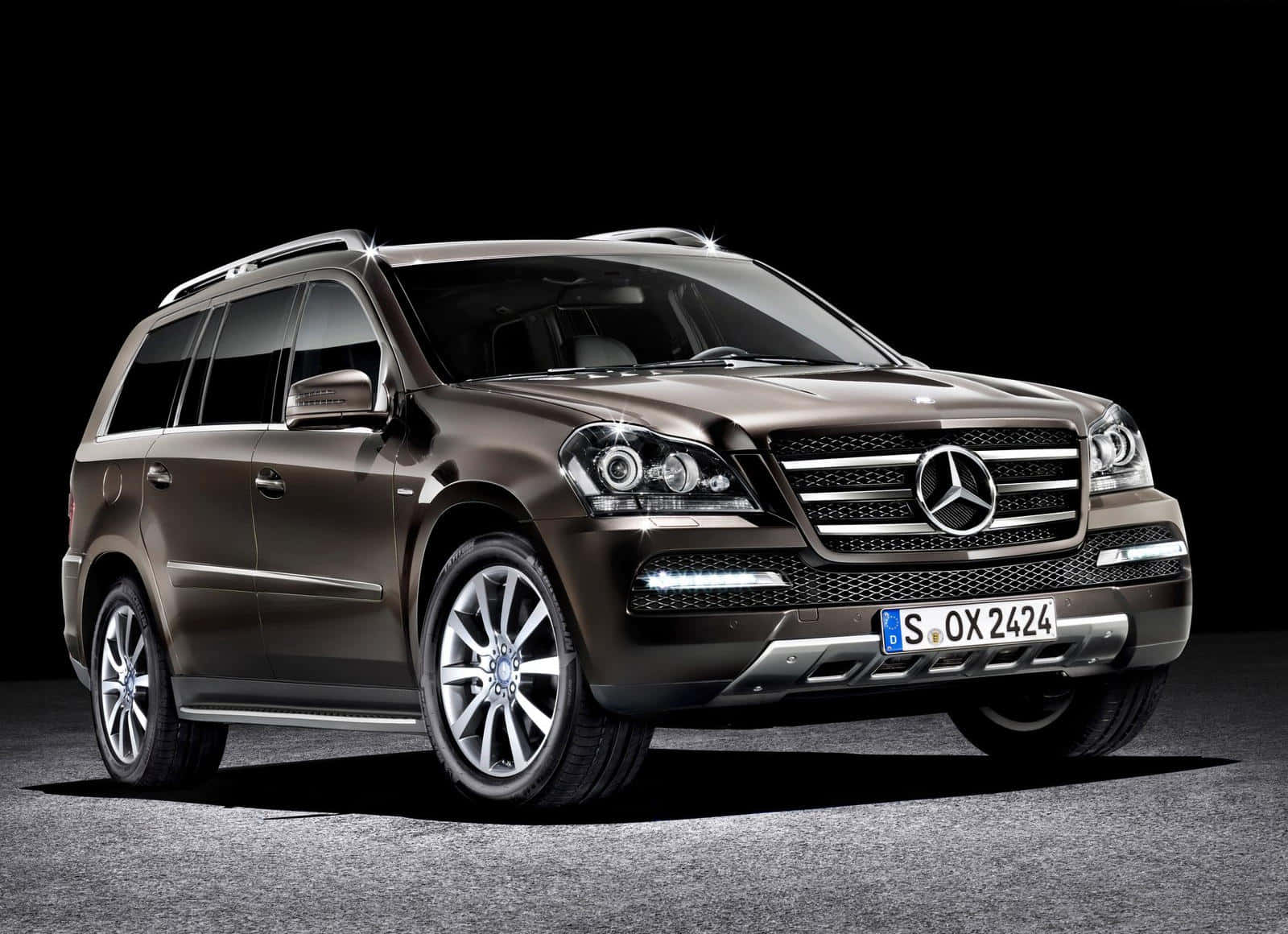 Mercedes-benz Gl-class 桌布 壁紙 — 一輛時尚的青銅色 Mercedes-Benz GL SUV 在攝影棚燈光下，於純黑背景中閃耀。