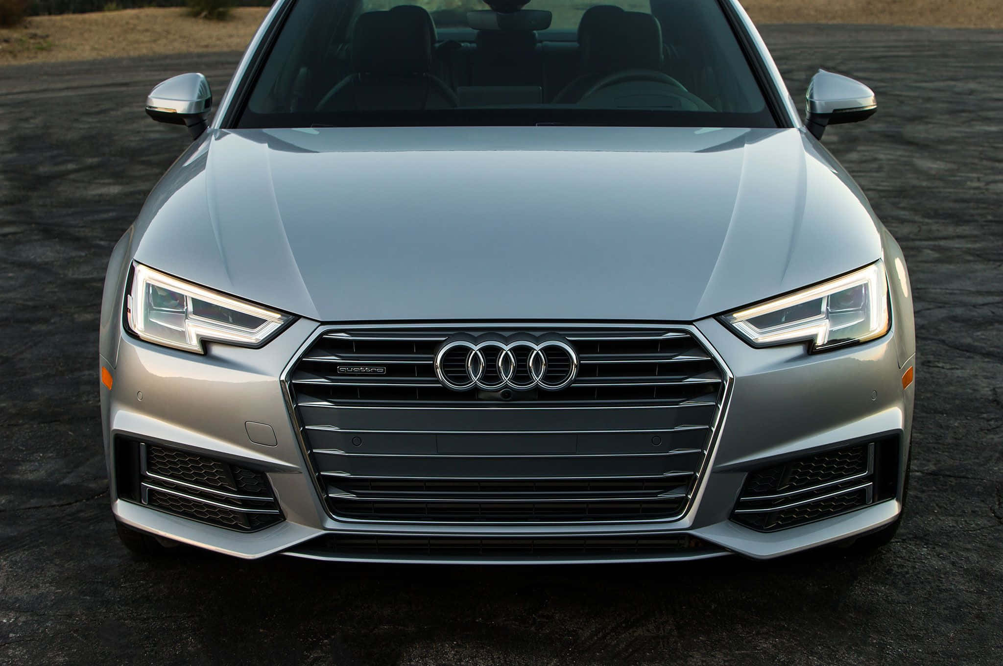 Audi A4 桌布 壁紙 — 一輛時尚的銀色奧迪轎車停在瀝青路上，帶有鋒利的前燈和標誌性的四環標誌的正面視圖。