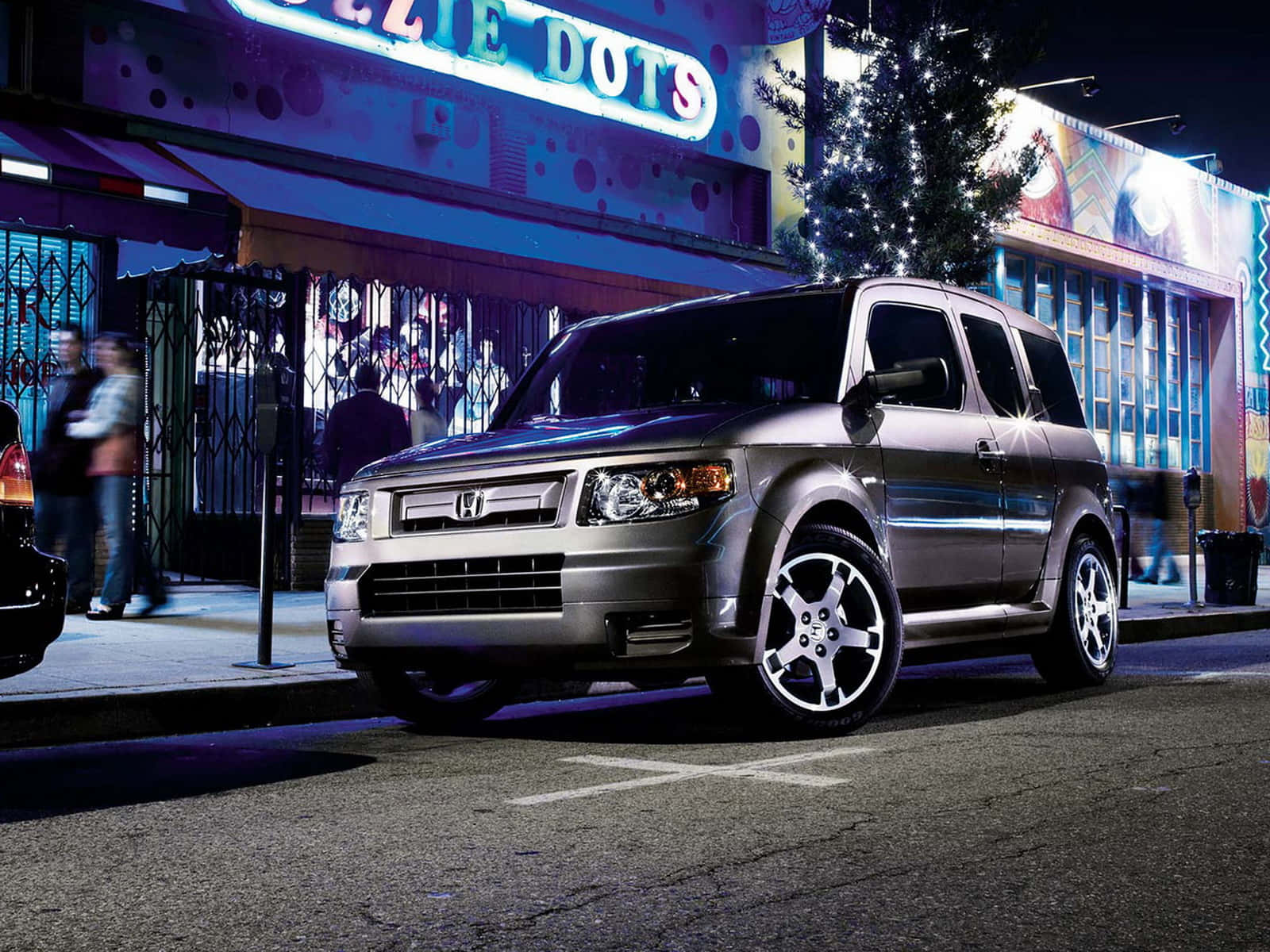 Honda Element 桌布 壁紙 — 一輛銀色本田Element停泊在夜晚充滿活力的霓虹燈城市街道上，伴有節日燈飾和行人。
