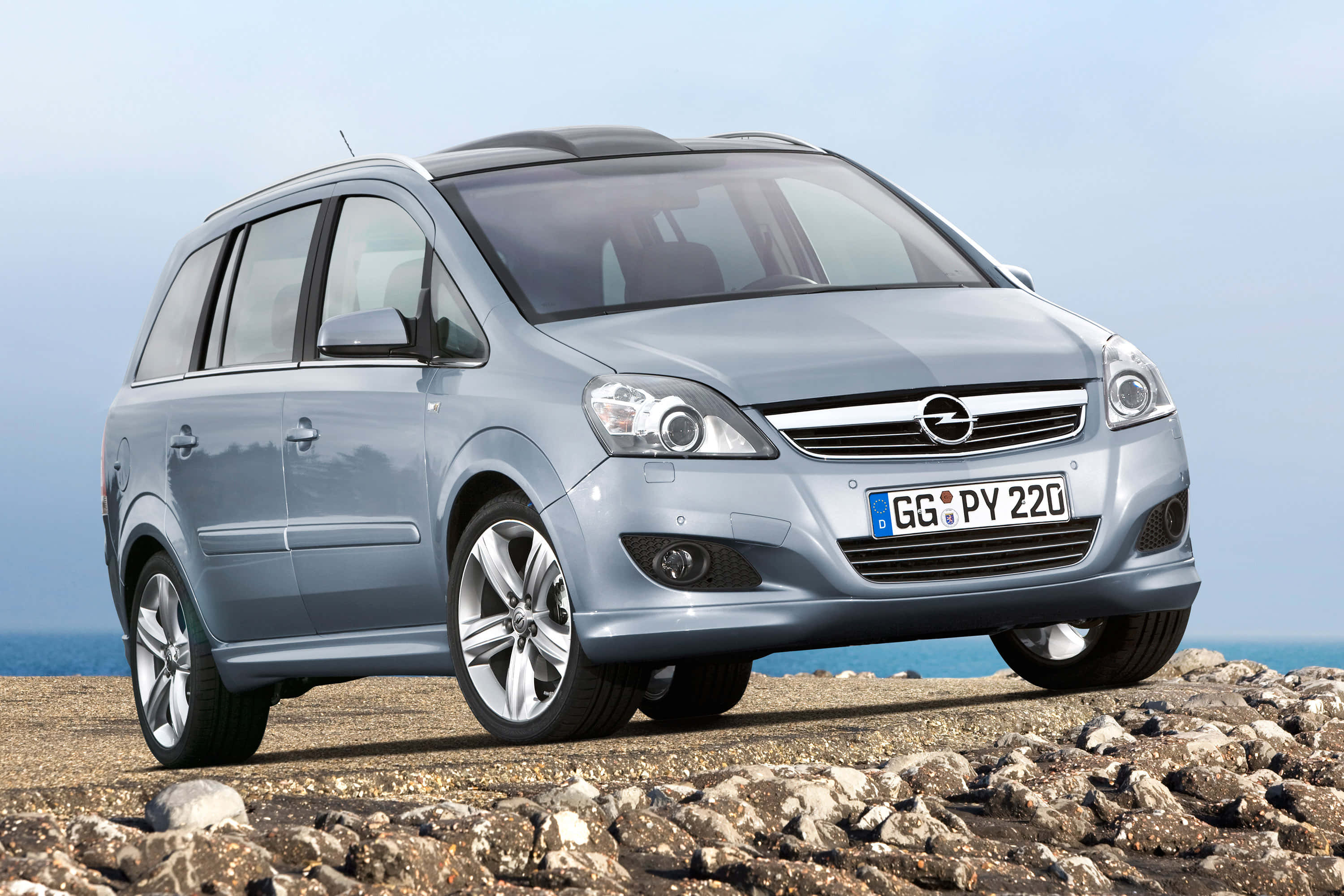 Opel Zafira 桌布 壁紙 — 一輛銀色歐寶Zafira停泊在岩石海岸懸崖上，俯瞰海洋，天空晴朗。