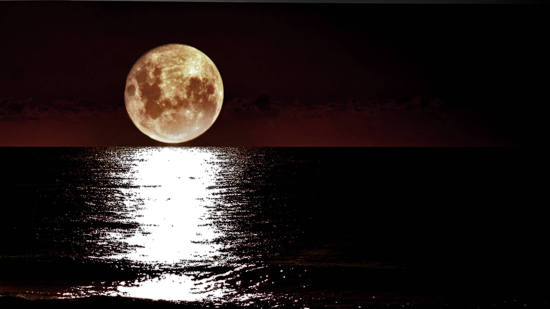 滿月映照在夜間平靜的海水上，天空呈深紅色