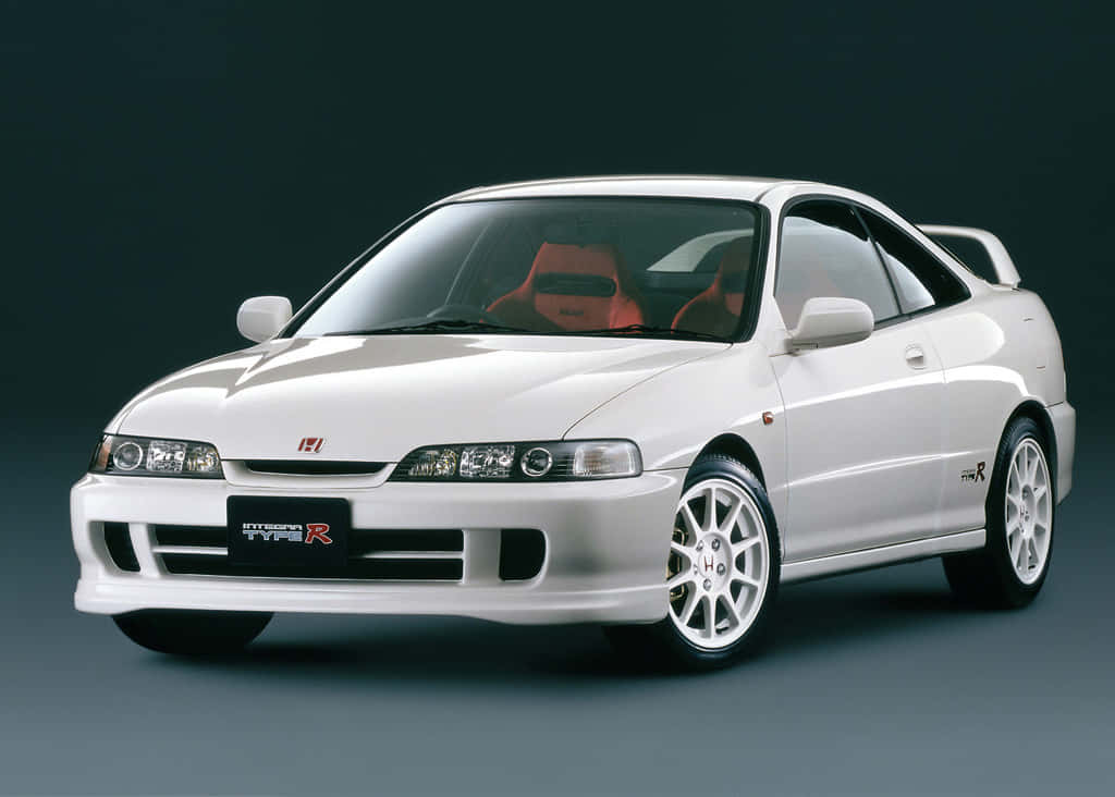 Honda Integra 桌布 壁紙 — 一輛純白色的本田Integra Type R運動轎跑車，配備紅色座椅和銀色輪圈，在深色工作室背景下展示。