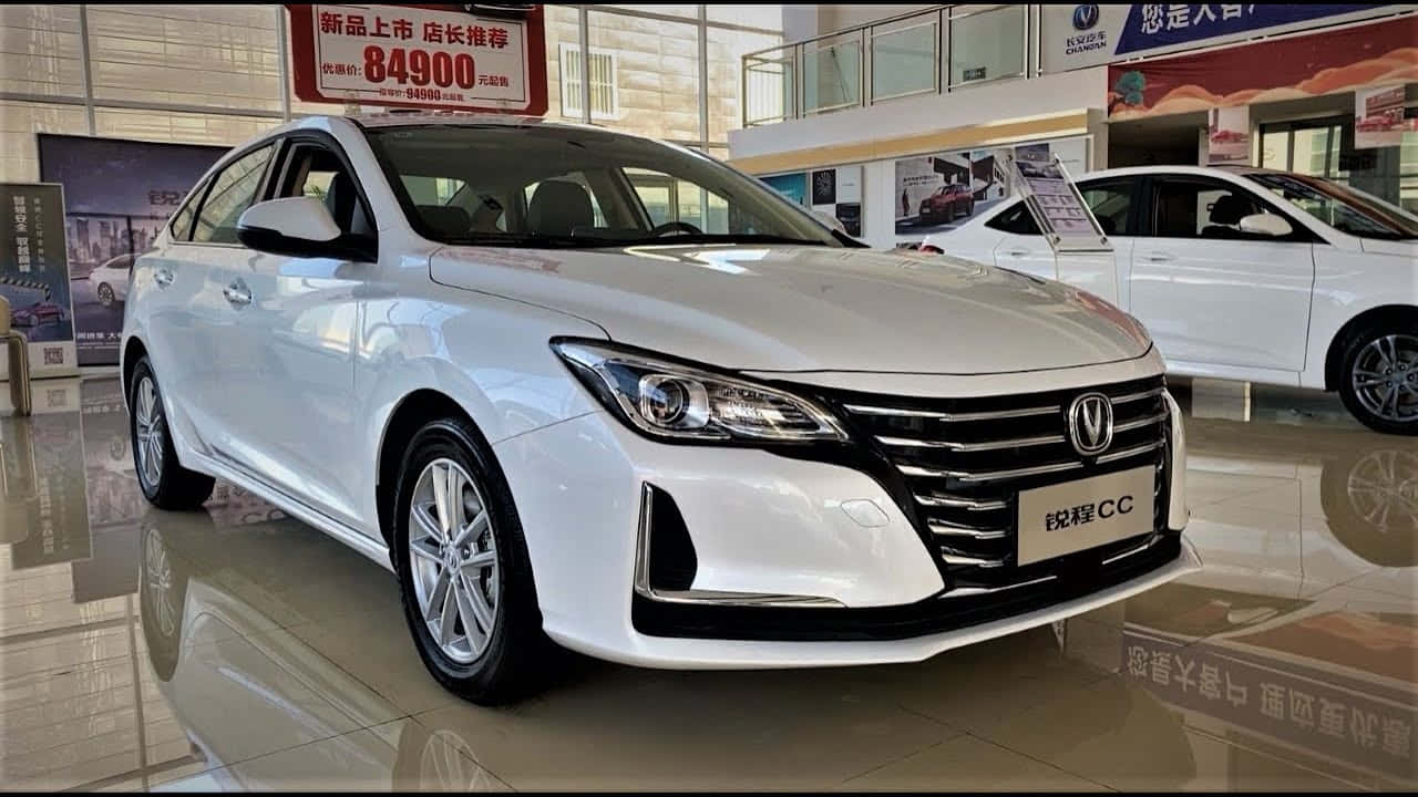  壁紙 — 一輛純白色的長安CC轎車在展廳燈光下閃閃發光，拋光地板反射出其時尚的現代設計。
