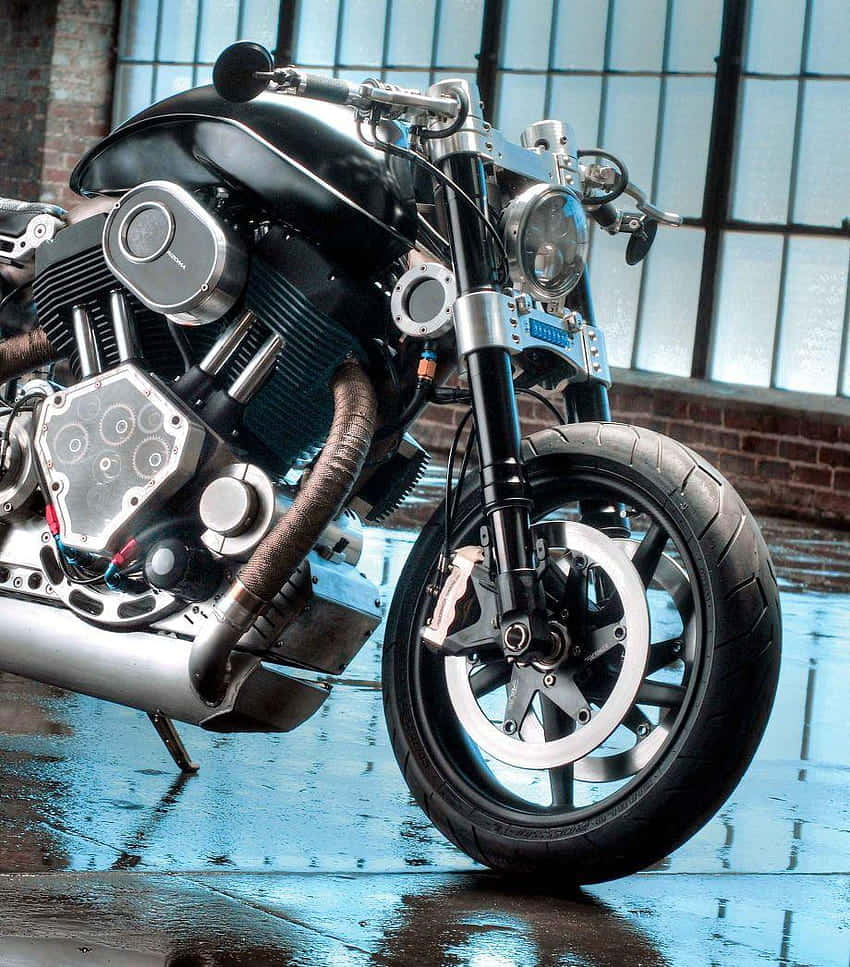 Confederate Motorcycle 桌布 壁紙 — 一輛帶有鍍鉻裝飾的定制黑色電單車停在大工業窗戶下的濕瀝青路面上。