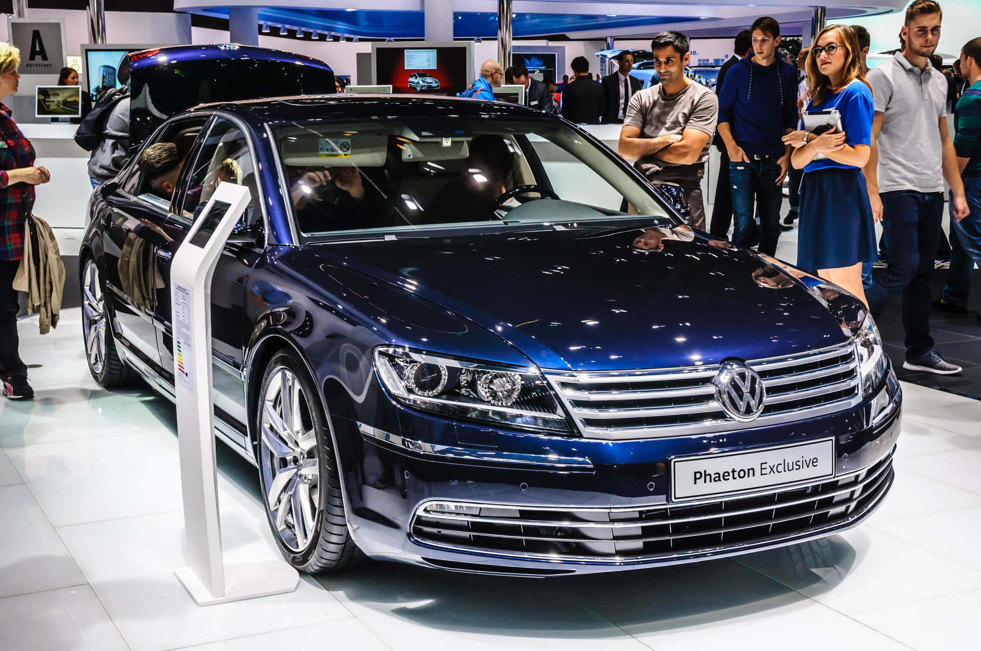  壁紙 — 一輛閃亮的藍色Volkswagen Phaeton Exclusive房車在車展上展出，周圍有參觀者觀看。