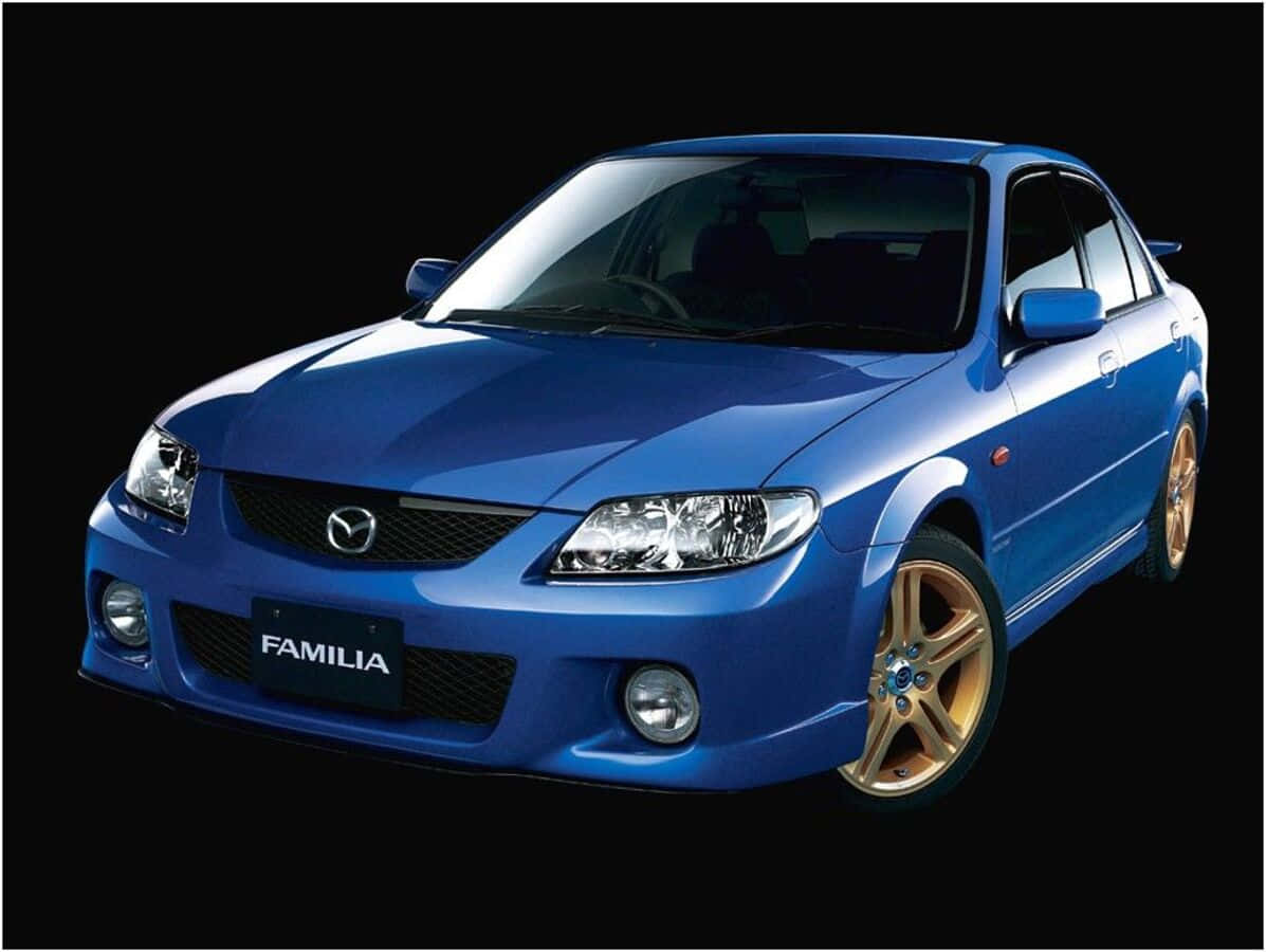 Mazda Protege 桌布 壁紙 — 一輛閃亮的藍色萬事得Familia房車配金色輪圈，在純黑背景下格外突出。