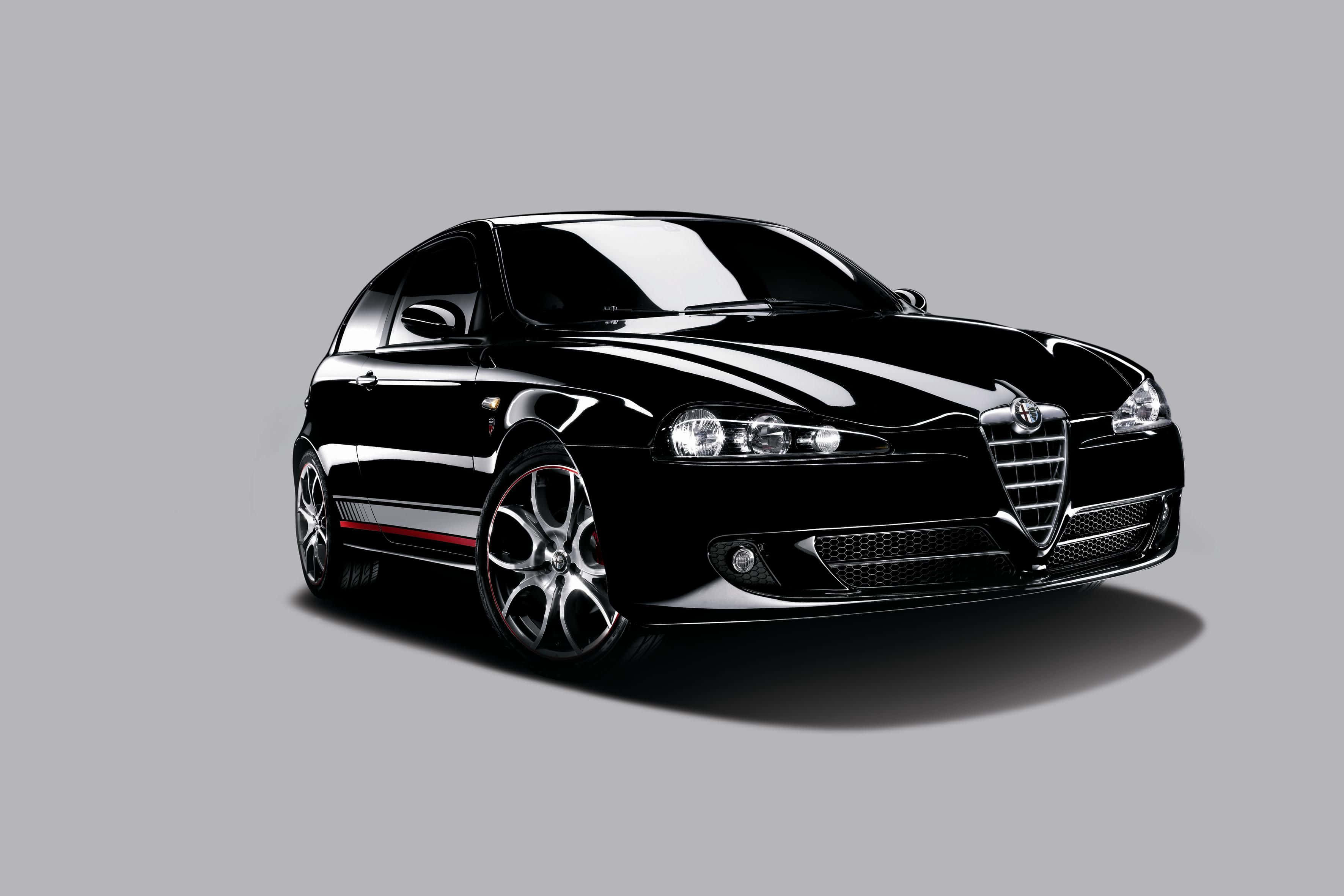 Alfa Romeo 147 桌布 壁紙 — 一輛時尚的黑色愛快羅密歐跑車，帶有紅色點綴和鍍鉻輪圈，在純灰色背景前蓄勢待發。