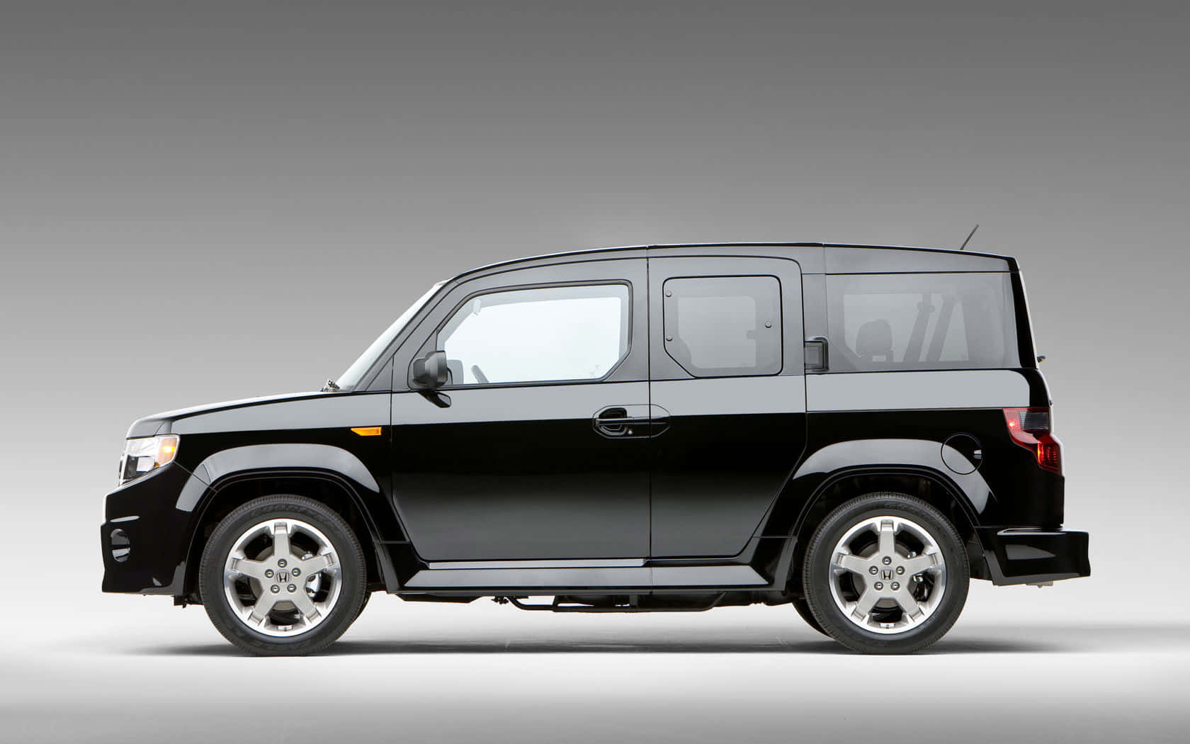 Honda Element 桌布 壁紙 — 一輛時尚的黑色本田 Element SUV 在側面展示，背景為中性灰色工作室背景。