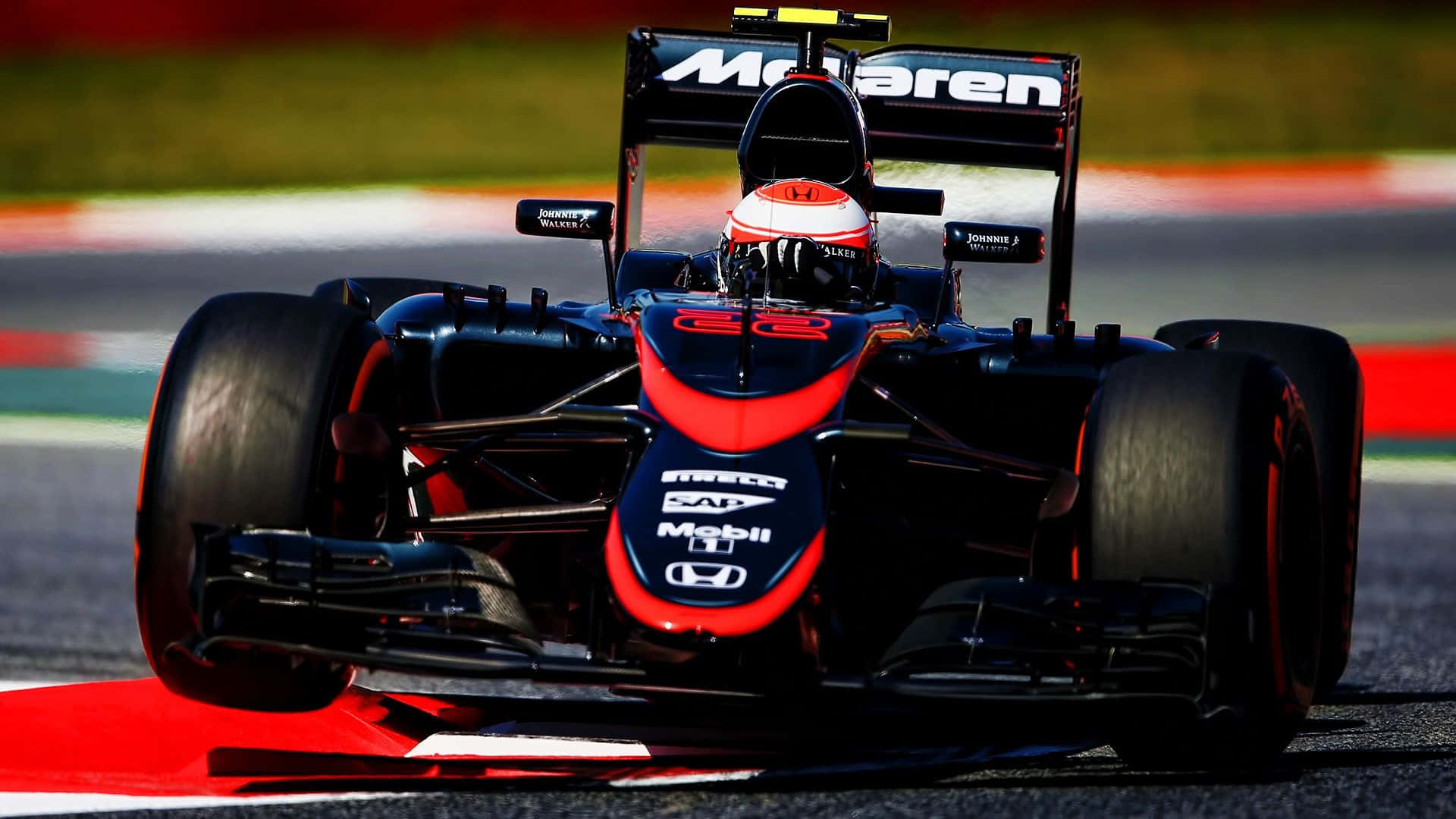 Mclaren F1 桌布 壁紙 — 一輛時尚的黑色和紅色麥拿侖一級方程式賽車在賽道上疾馳，車手戴著紅白頭盔。