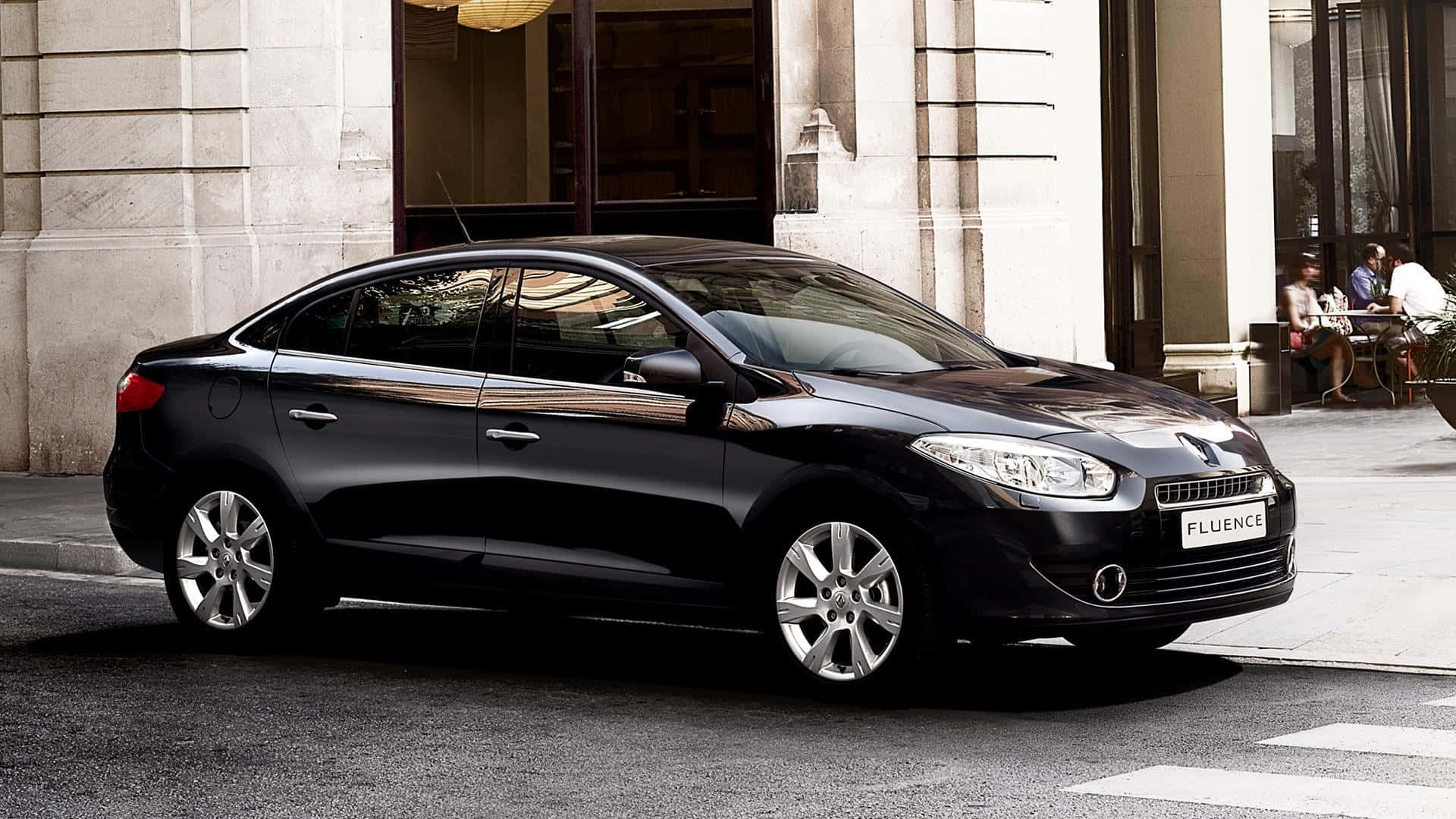 Renault Fluence 桌布 壁紙 — 一輛時尚的黑色雷諾Fluence轎車停泊在城市街道上，旁邊是一座石建築，人們在戶外用餐。
