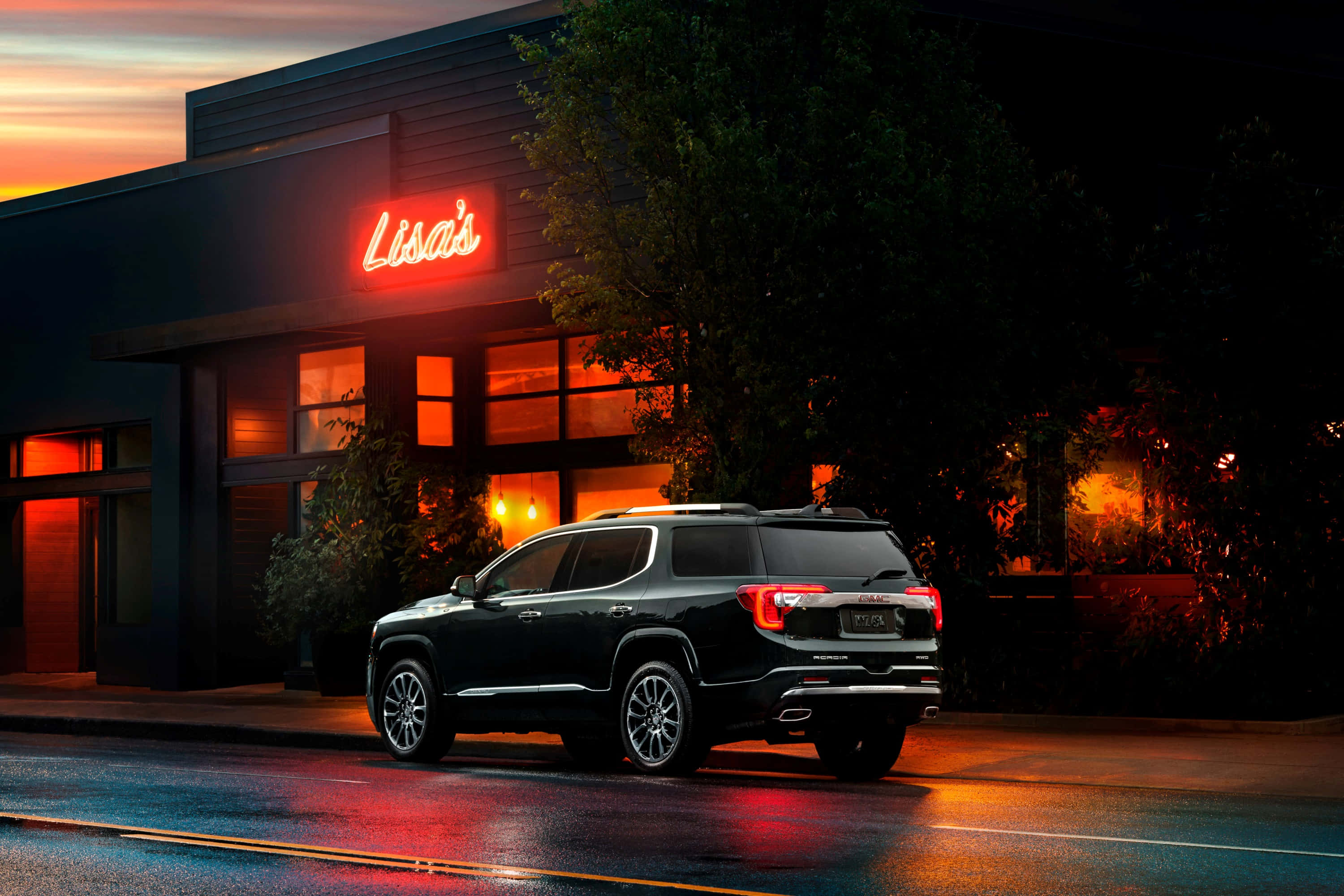 Gmc Acadia 桌布 壁紙 — 一輛時尚的黑色SUV在黃昏時停泊在濕漉漉的街道上，被寫著Lisa's的霓虹燈招牌的溫暖光芒照亮。