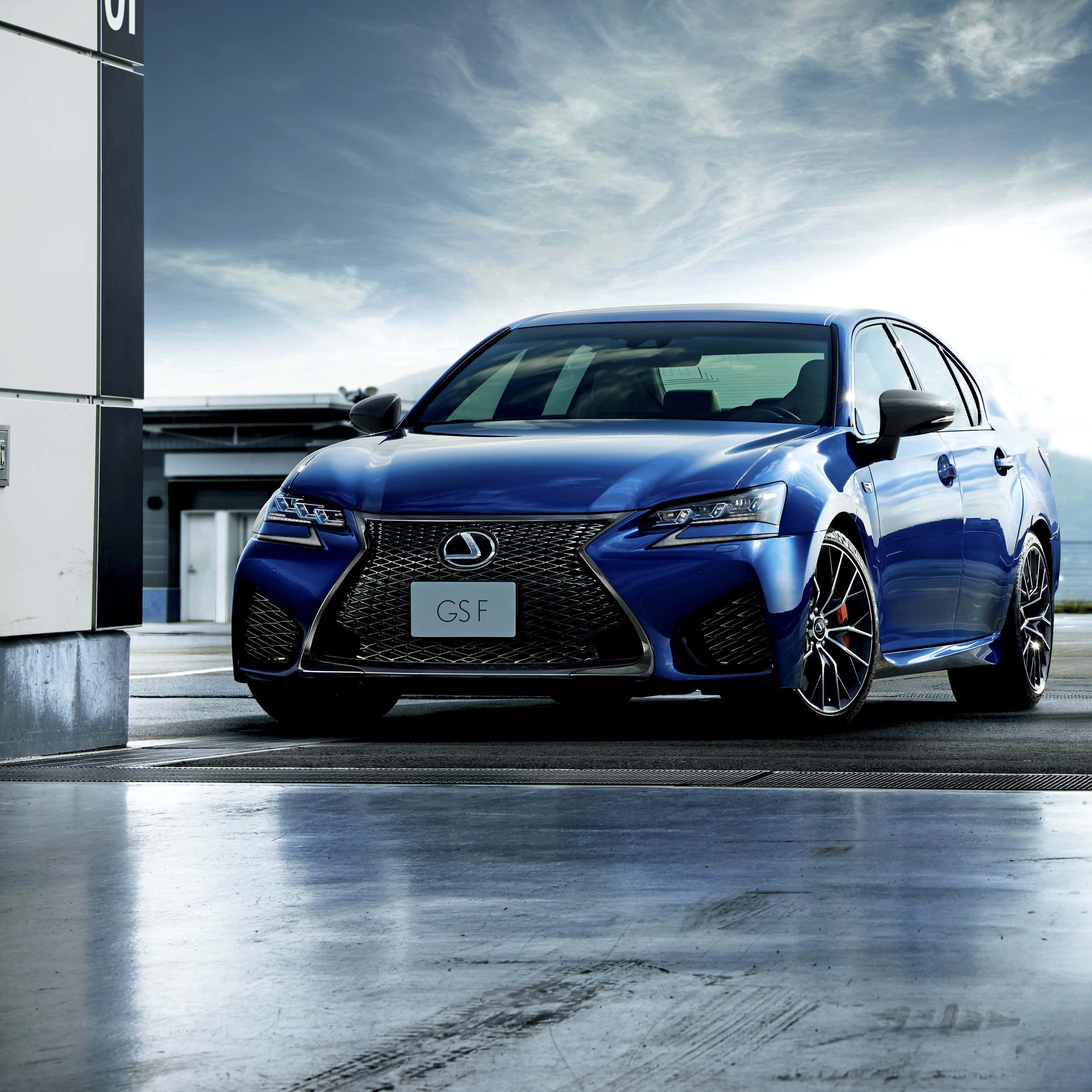 Lexus Gs F 桌布 壁紙 — 一輛時尚的藍色Lexus GS F運動轎車在現代都市環境中，在戲劇性的多雲天空下閃閃發光。