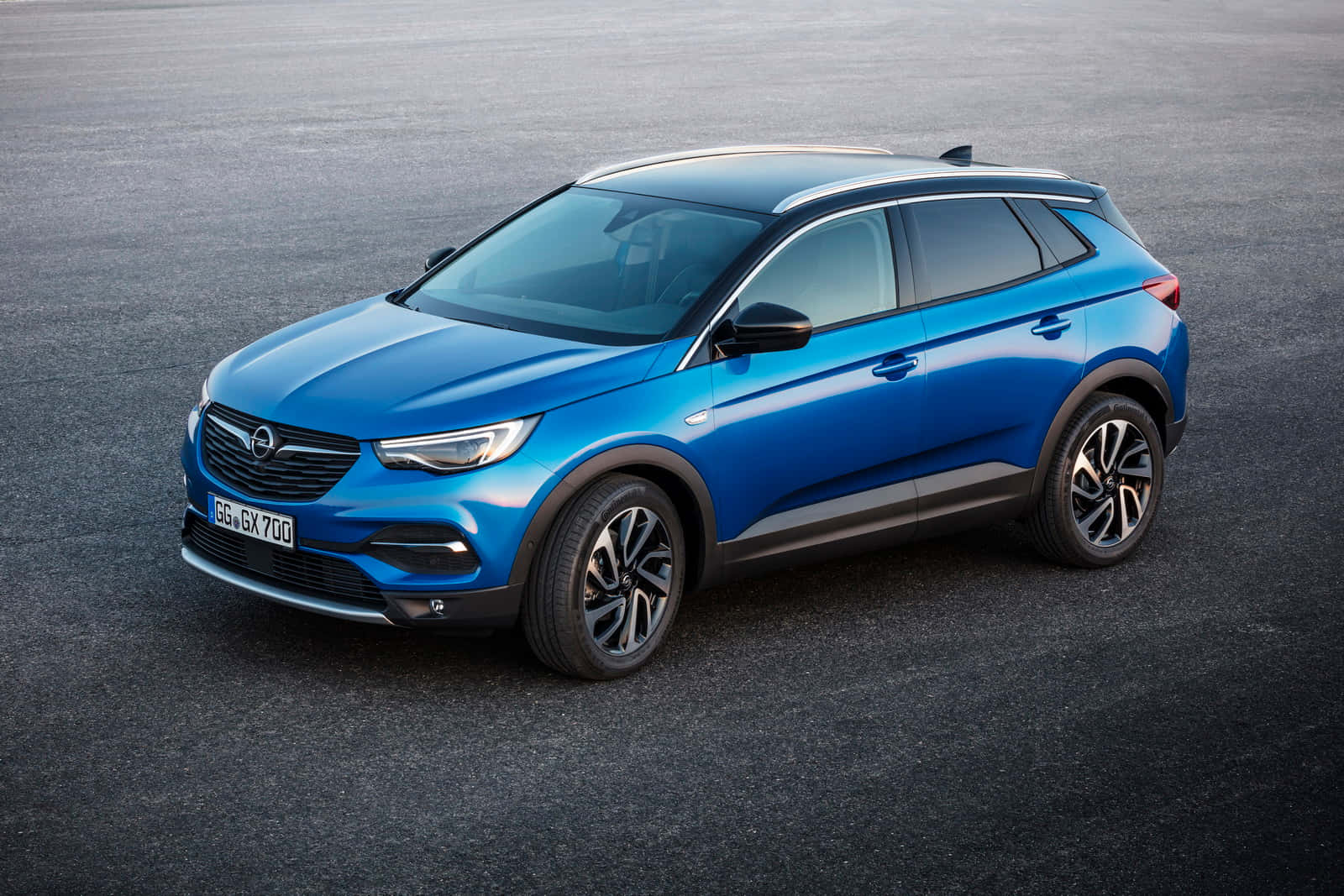 Opel Grandland X 桌布 壁紙 — 一輛時尚的藍色歐寶跨界SUV在明亮的日光下停泊在灰色瀝青路面上。