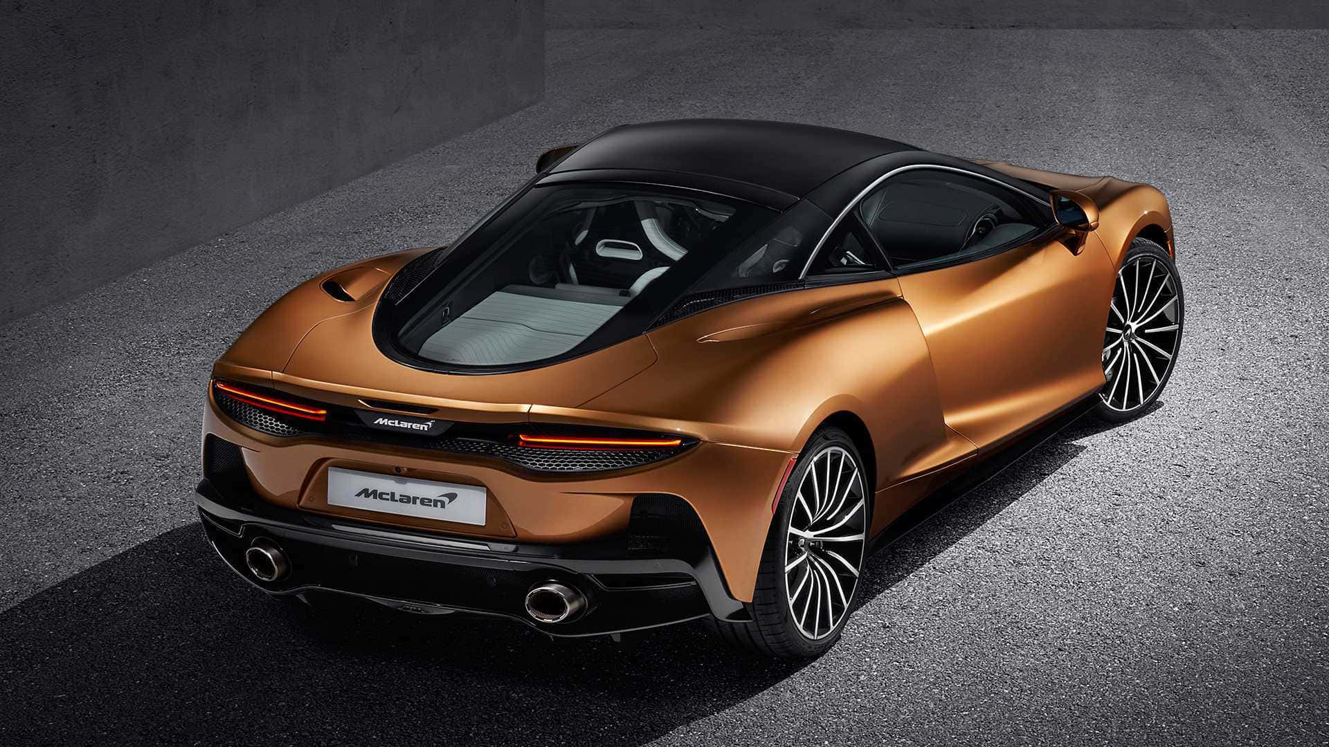 Mclaren Gt 桌布 壁紙 — 一輛時尚的銅色McLaren跑車，黑色車頂和車輪，在深色混凝土表面上從上方觀看。