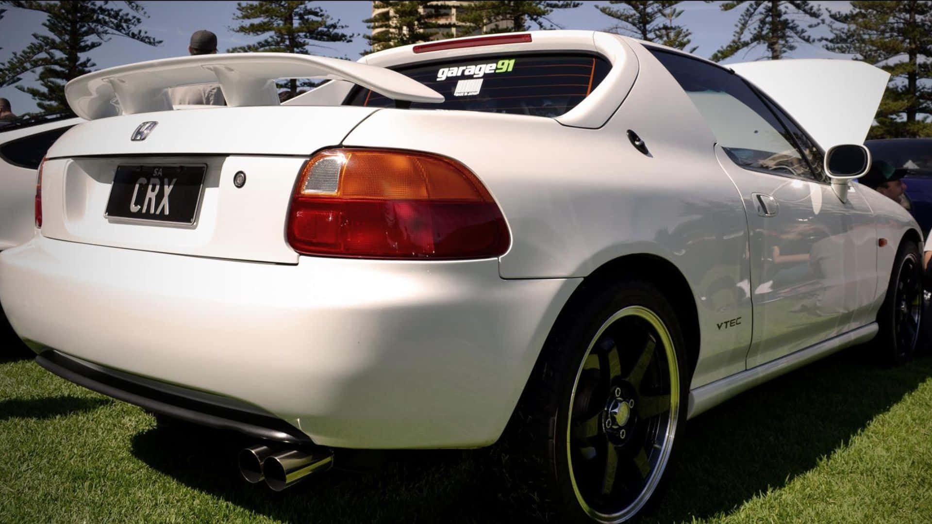 Honda Civic Del Sol 桌布 壁紙 — 一輛純白色的本田CRX跑車，引擎蓋打開，停泊在明亮的日光下的綠色草地上。