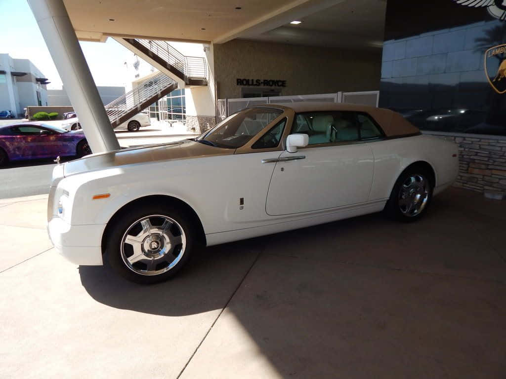 Rolls Royce Phantom Drophead Coupe 桌布 壁紙 — 一輛純白色的勞斯萊斯 Phantom Drophead Coupe 停放在經銷商天篷下，配備鍍鉻輪圈和米色敞篷車頂。
