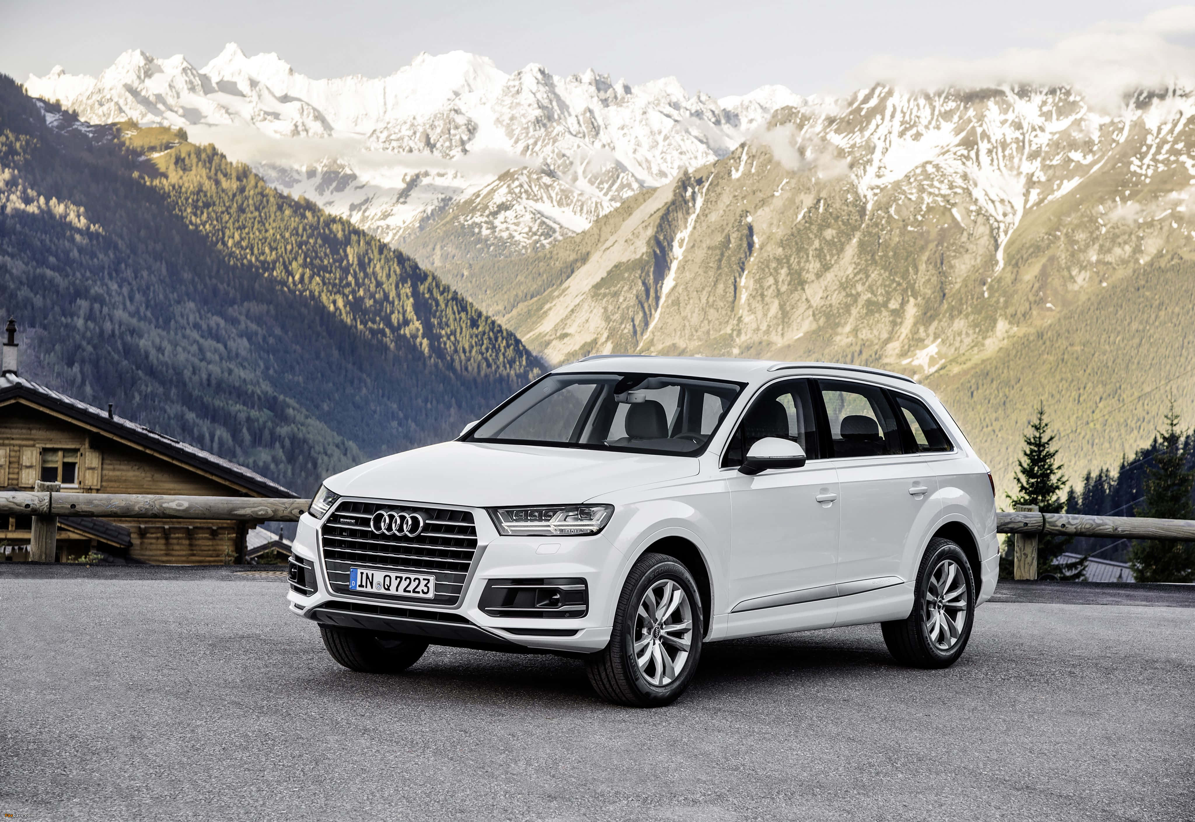 Audi Q7 桌布 壁紙 — 一輛純白色的奧迪Q7 SUV停泊在山路上，背景是白雪覆蓋的山峰和木屋。