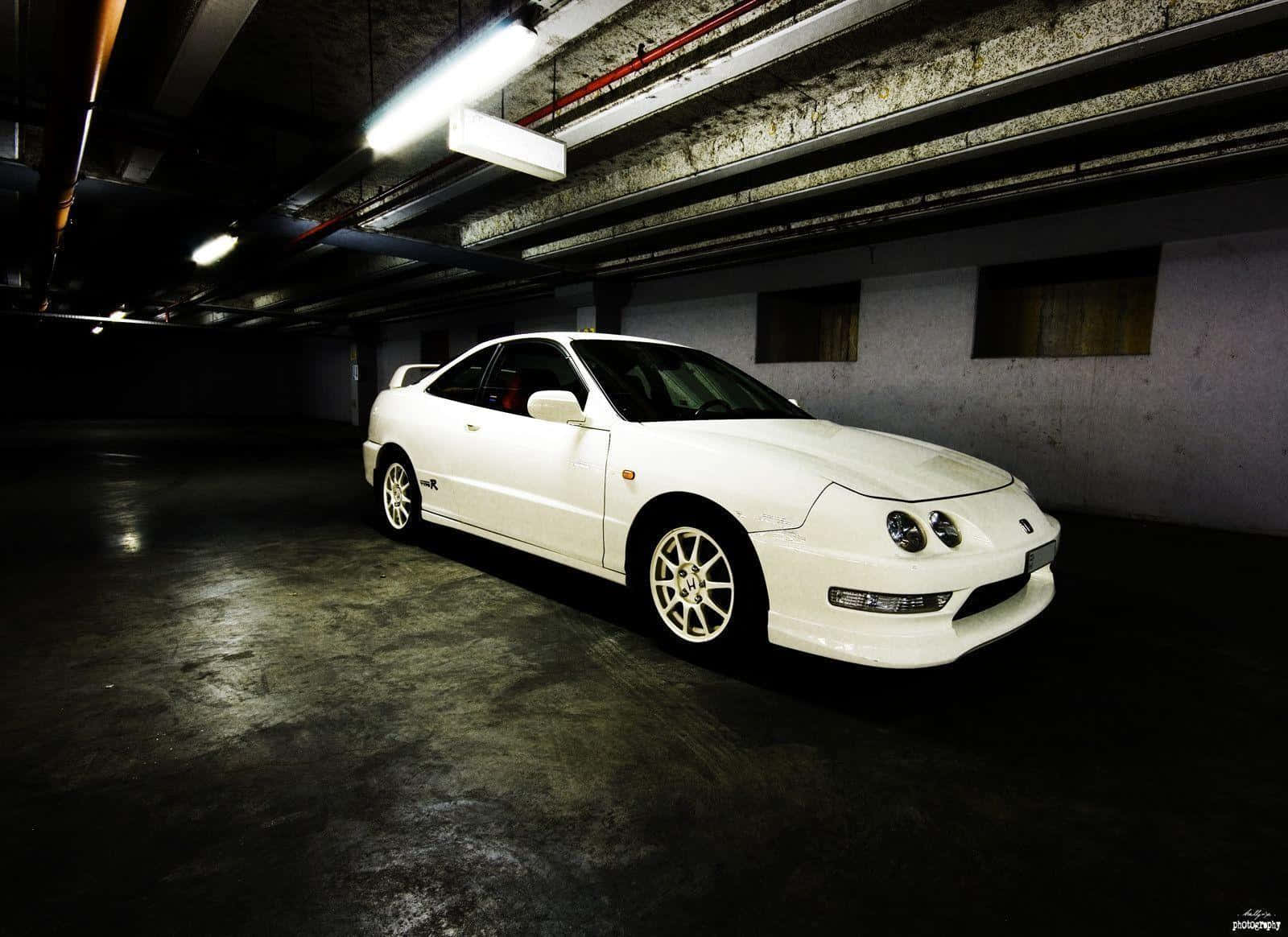Acura Integra 桌布 壁紙 — 一輛純白色運動轎跑車在惡劣的地下停車場中，在刺眼的螢光燈下閃閃發光。