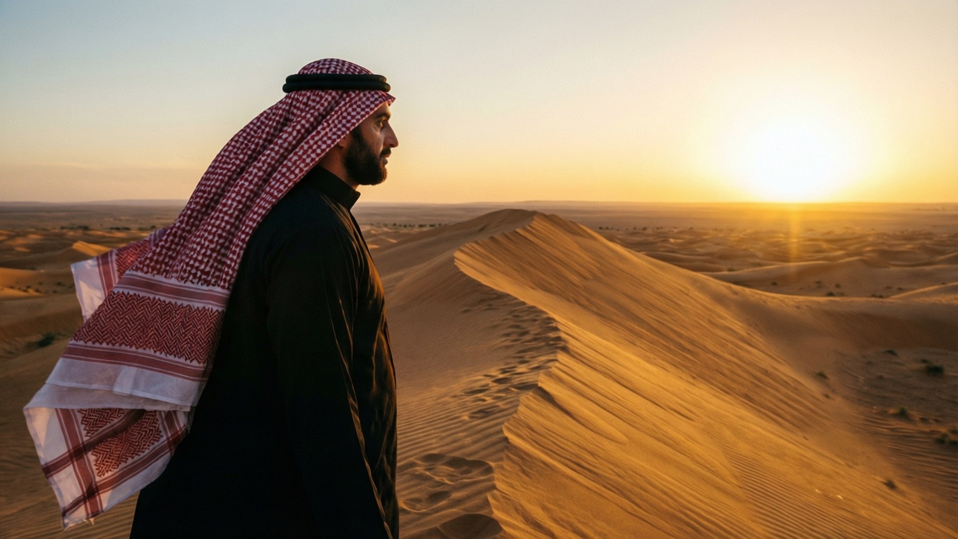 Desert Wanderer 壁紙 — 一名戴著傳統頭巾的男子在金色沙漠日落中形成剪影，在沙丘上投下長長的影子。