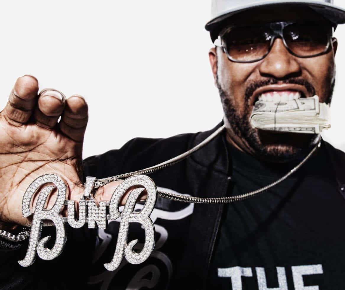  壁紙 — 一名戴著帽子和太陽眼鏡的男子手持鑲滿鑽石的「Bun B」鏈條，嘴裡露出鈔票。