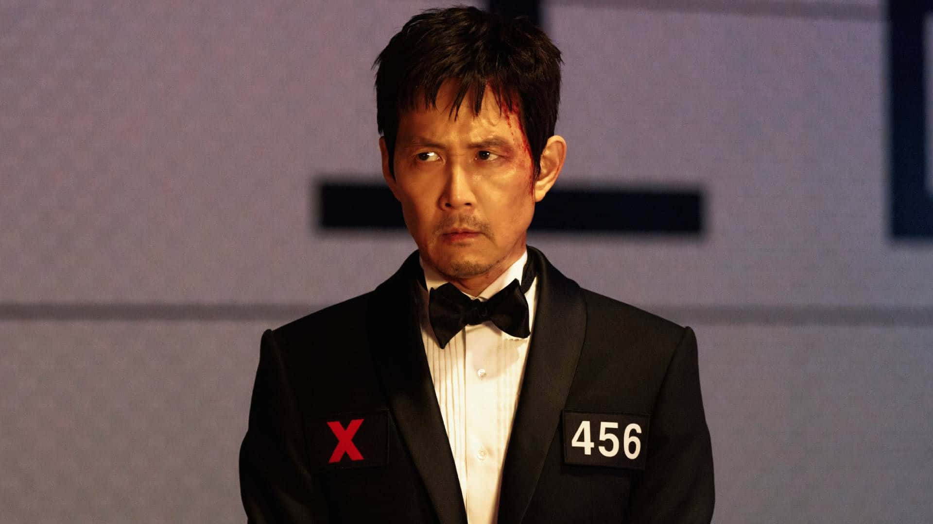  壁紙 — 一名身穿黑色燕尾服的男子，領口上有紅色X和數字456，額頭上有血，專注地凝視。