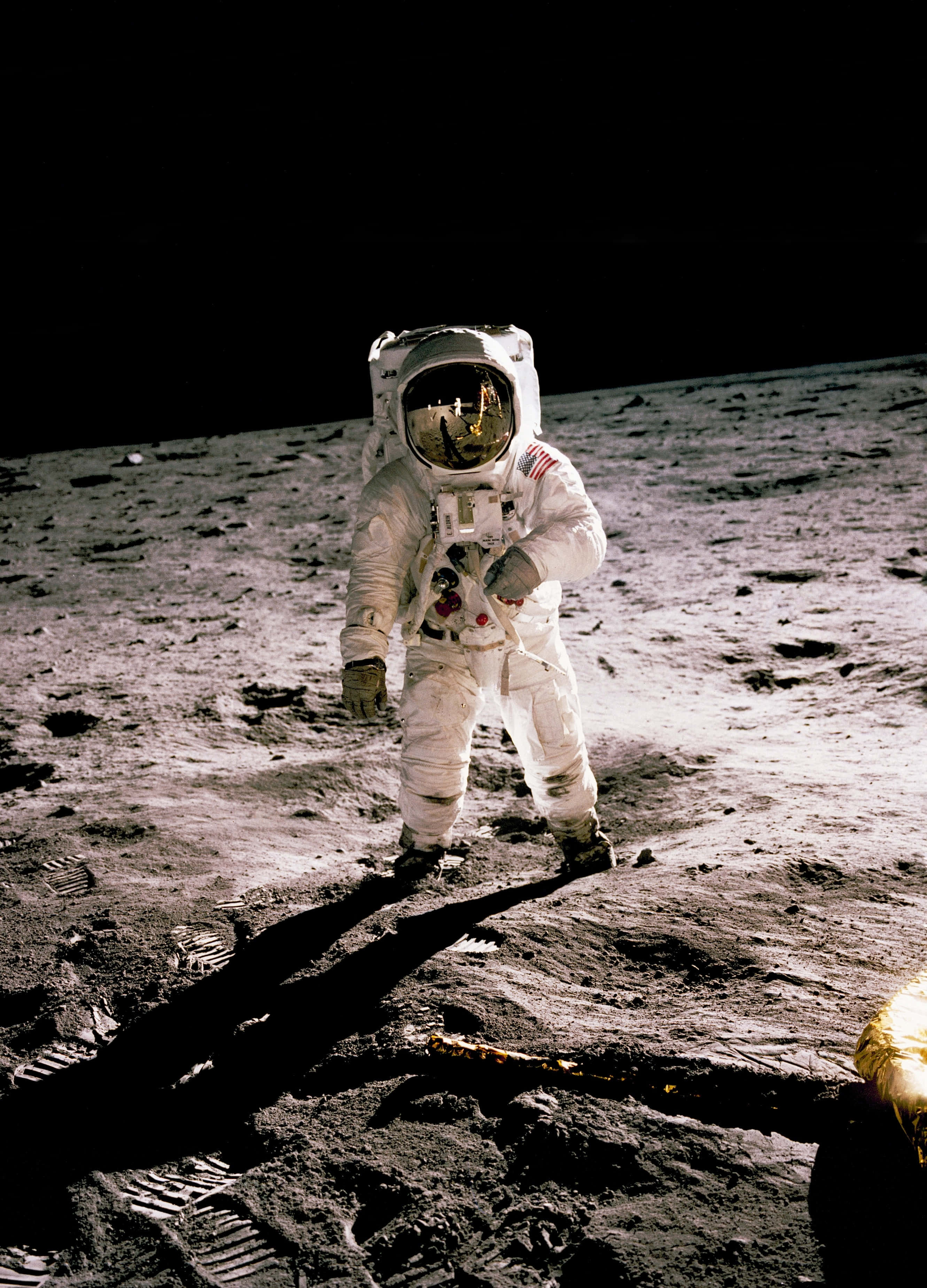 Neil Armstrong 桌布 壁紙 — 一名身穿白色太空衣的太空人站在月球灰色的表面上，在強烈的陽光下投下長長的影子。