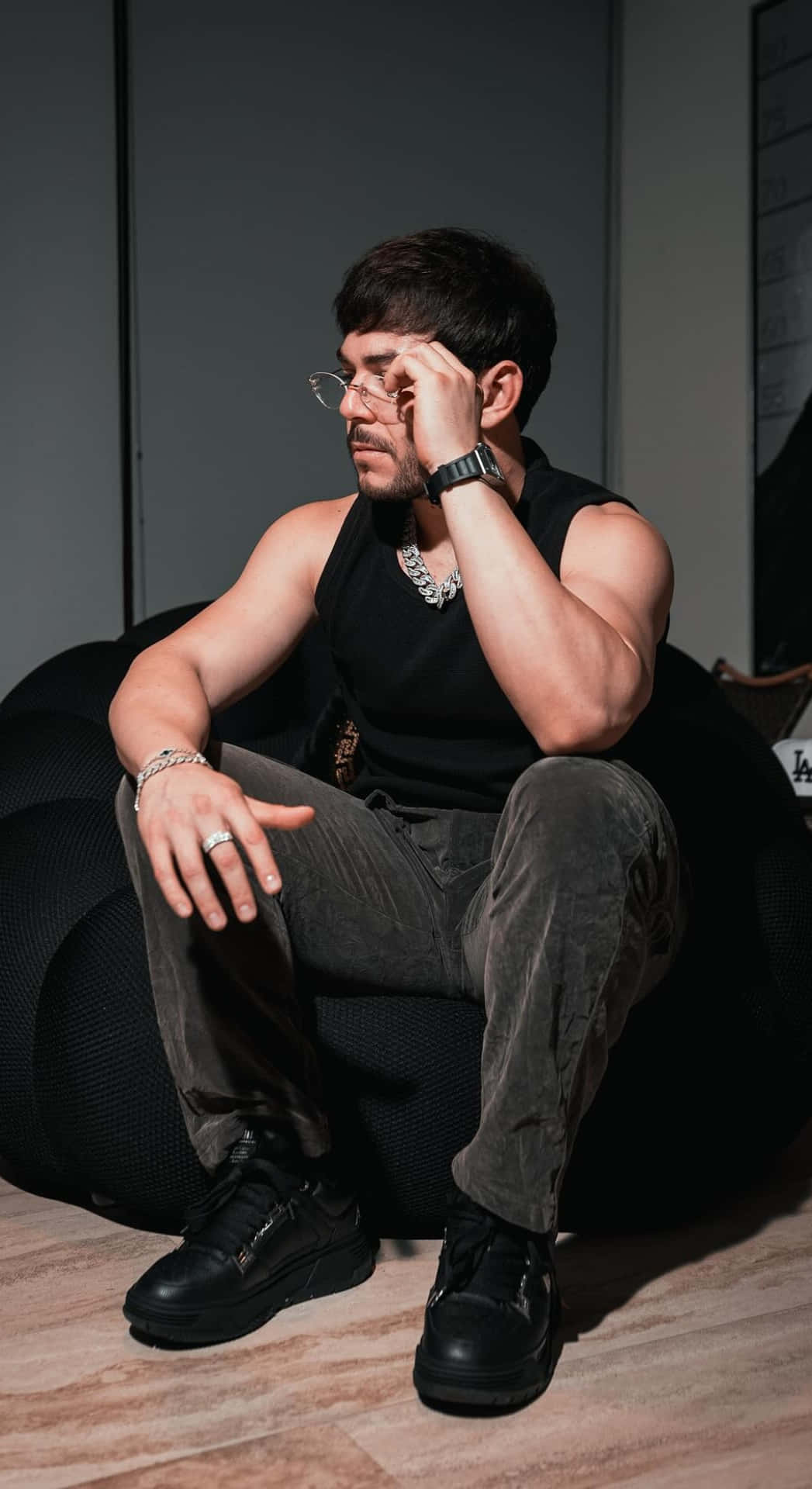  壁紙 — 一名身穿黑色背心及戴眼鏡的男子，在昏暗的房間裏若有所思地坐在豆袋椅上。