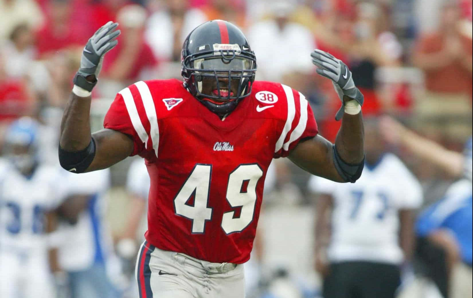  壁紙 — 一名身穿紅色 Ole Miss 49號球衣的足球員在日間比賽中舉臂慶祝。