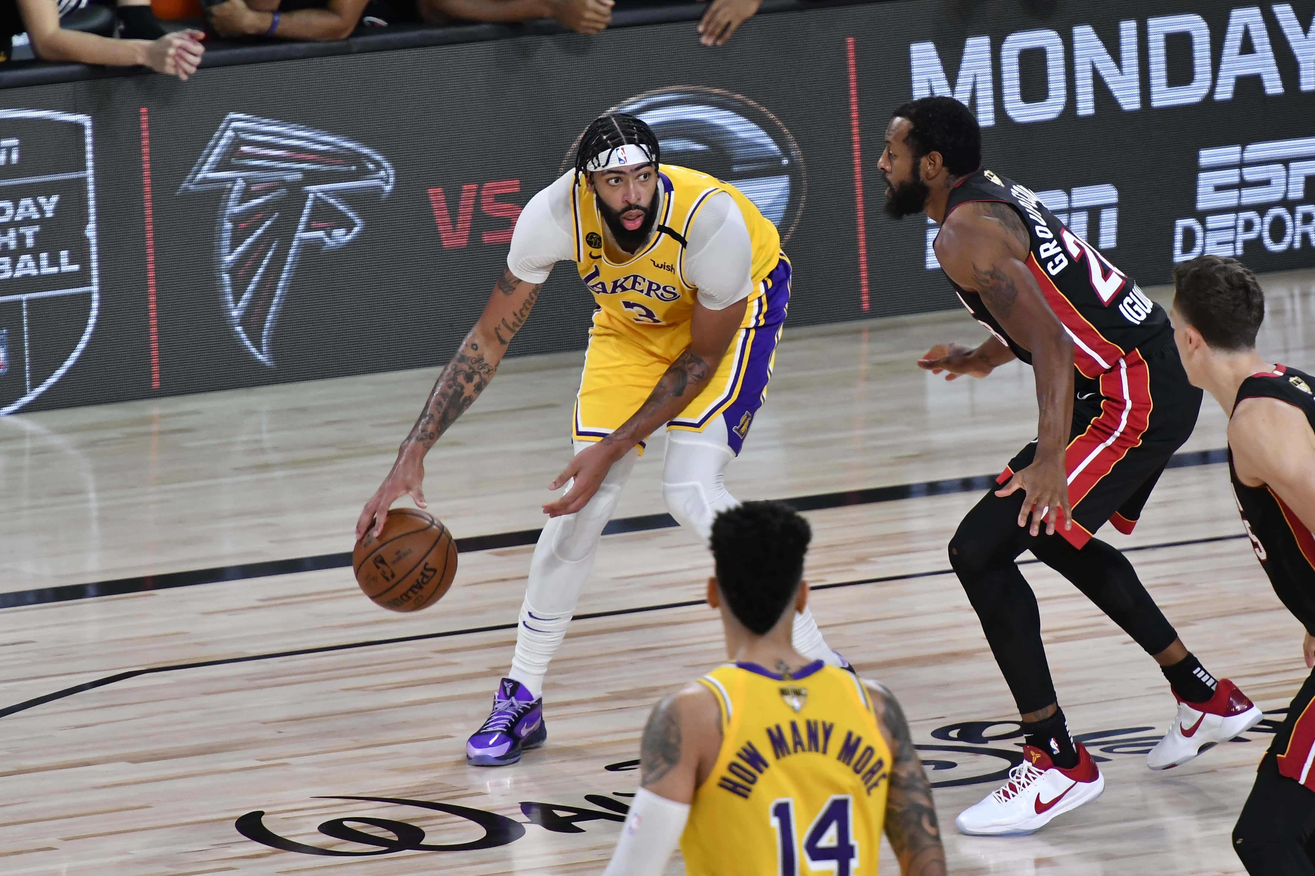 Lakers 2020 桌布 壁紙 — 一名身穿黃色湖人隊球衣的籃球運動員在燈光明亮的球場上運球，同時受到對手的防守。
