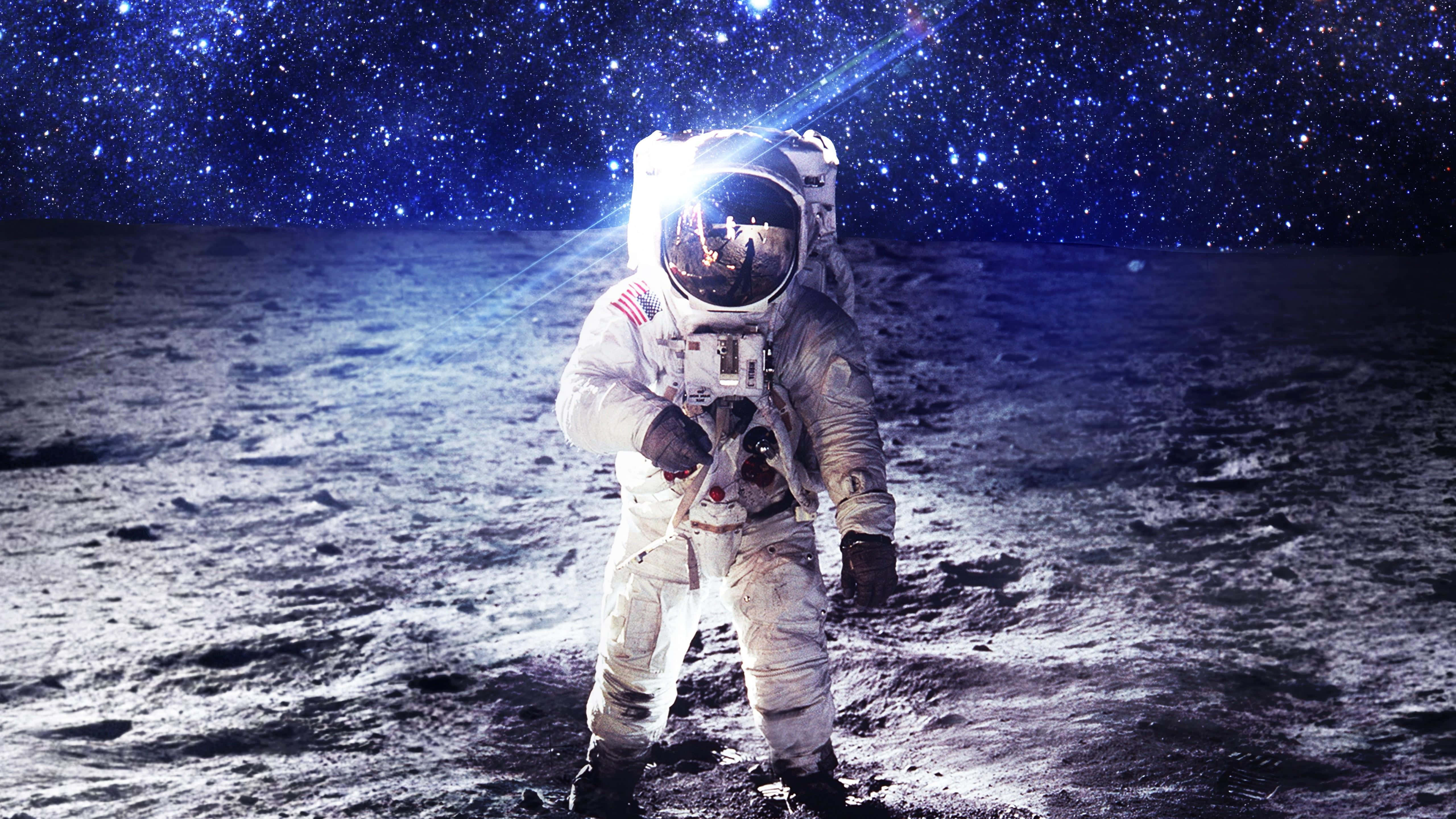 Neil Armstrong 桌布 壁紙 — 一名太空人站在月球表面，星空下，頭盔反射中可見地球。