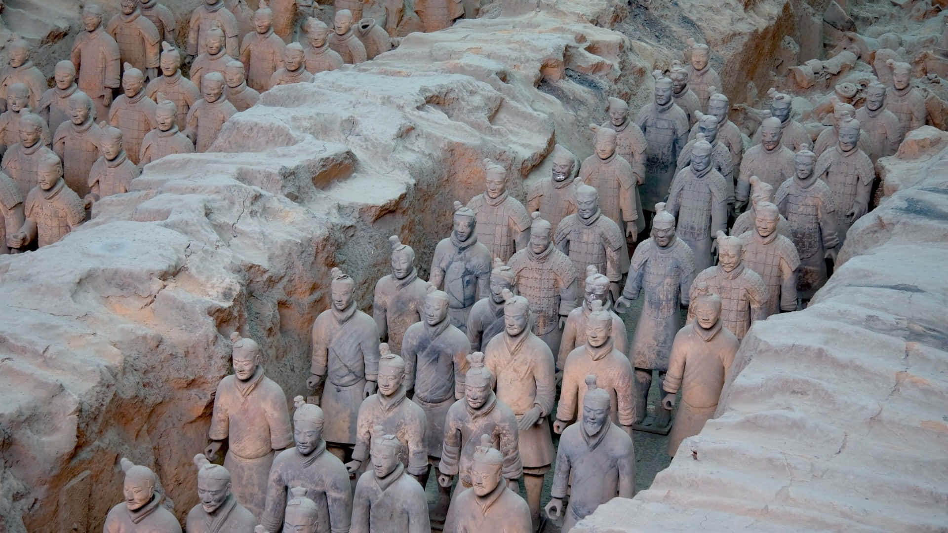  壁紙 — 一排排古老的兵馬俑站在泥土色的坑道中，柔和的光線顯露出精細的鎧甲和莊嚴的表情。