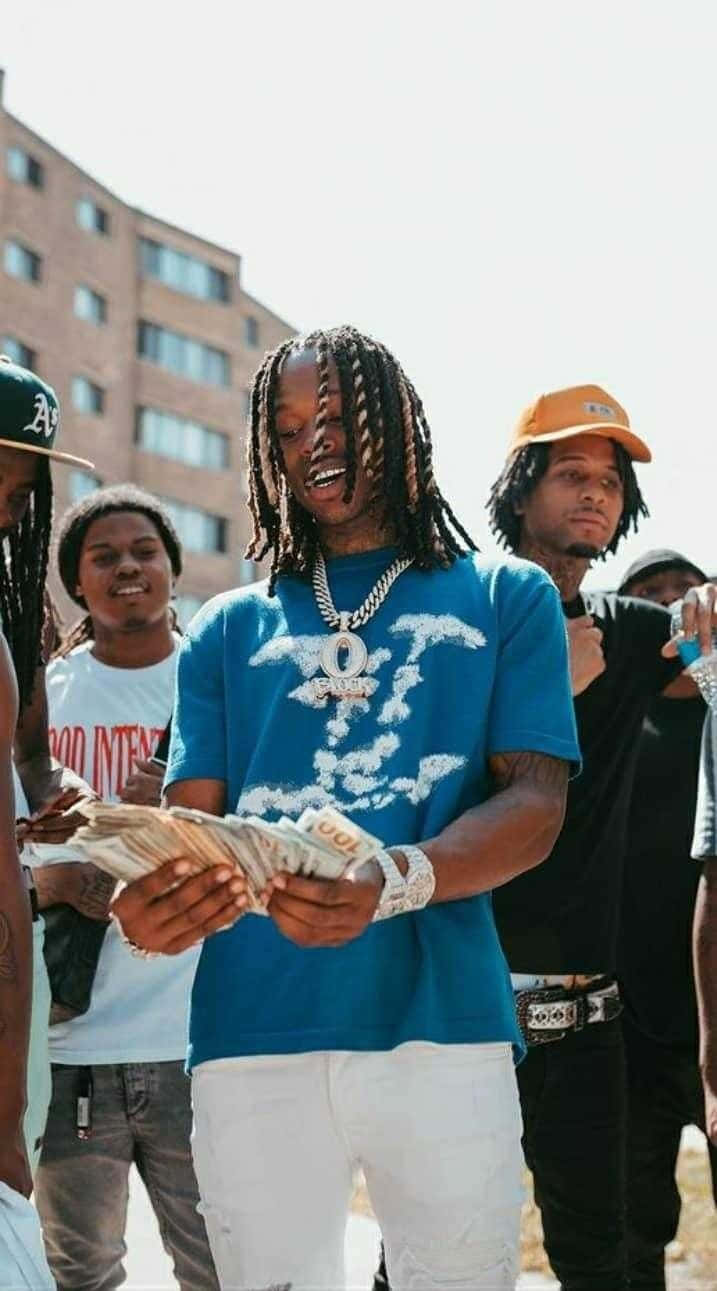  壁紙 — 一位辮子年輕男子在陽光普照的城市戶外與朋友們一起笑著手持一疊現金。