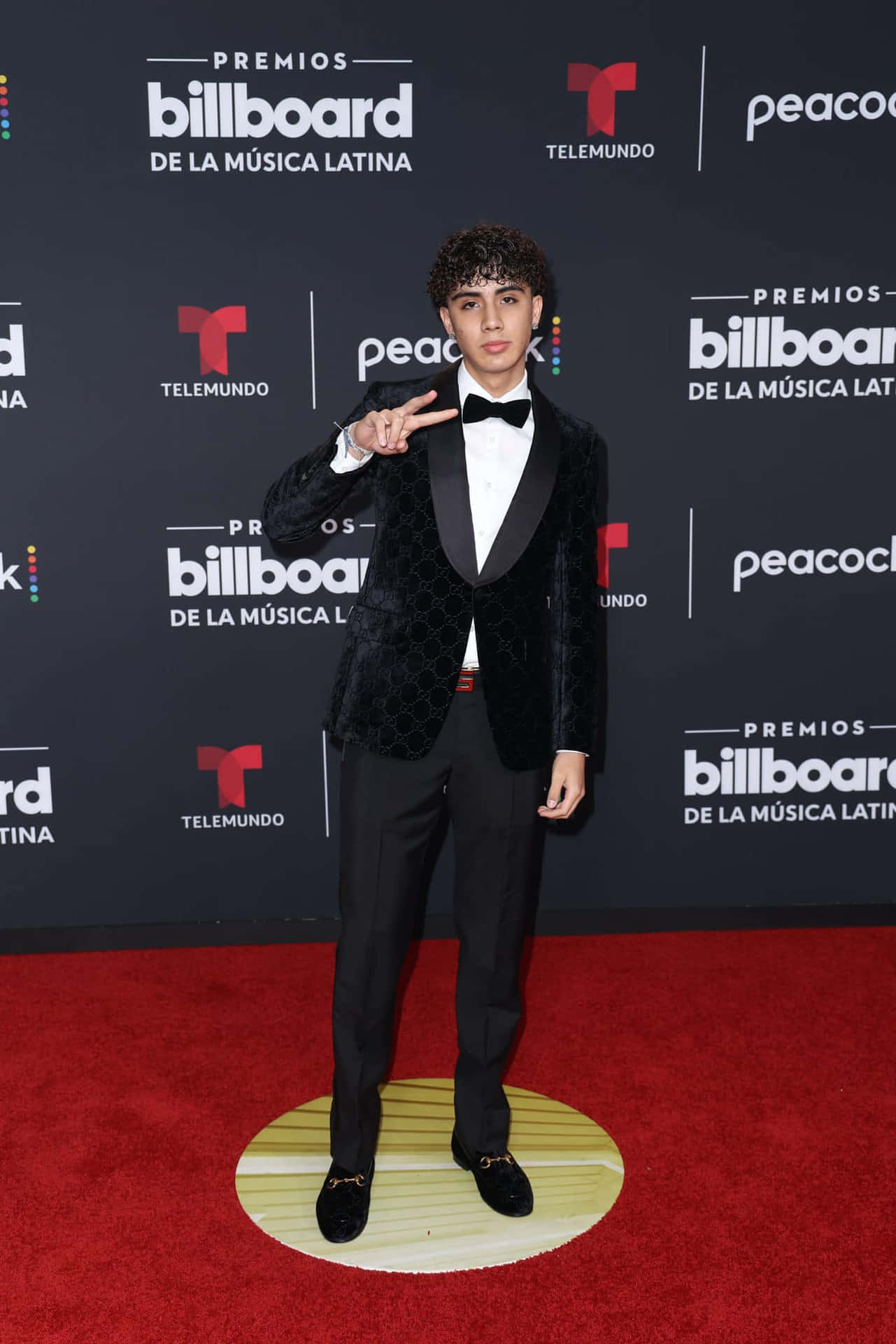  壁紙 — 一位身穿黑色天鵝絨燕尾服的年輕男子在Billboard拉丁音樂獎的紅地毯上自信地擺姿勢。