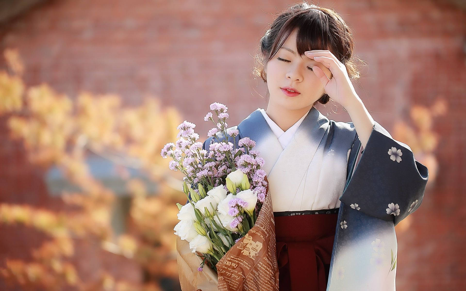 穿著和服的女性在秋季磚牆前手持花朵