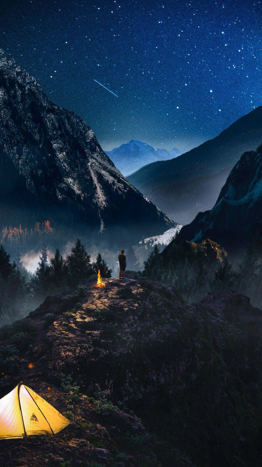  壁紙 — 一位孤獨的徒步旅行者夜晚站在山脊上，旁邊有營火，下方有發光的帳篷，在流星劃過的星空下。