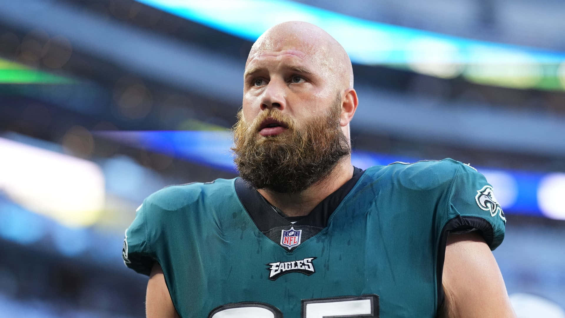  壁紙 — 一位光頭鬍鬚的足球員身穿綠色Eagles球衣，在球場燈光下專注地站在場上。