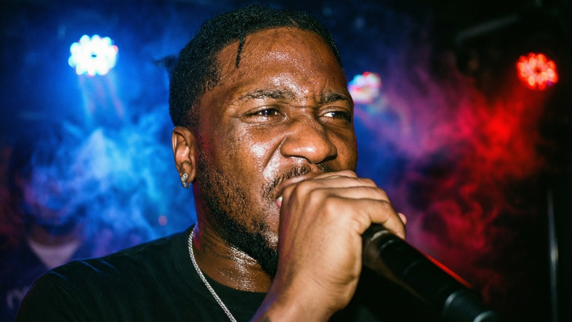 Fetty Wap 桌布 壁紙 — 一位汗流浹背的男饒舌歌手在充滿活力的藍色和紅色舞台燈光下，身後煙霧繚繞，熱情地對著麥克風表演。